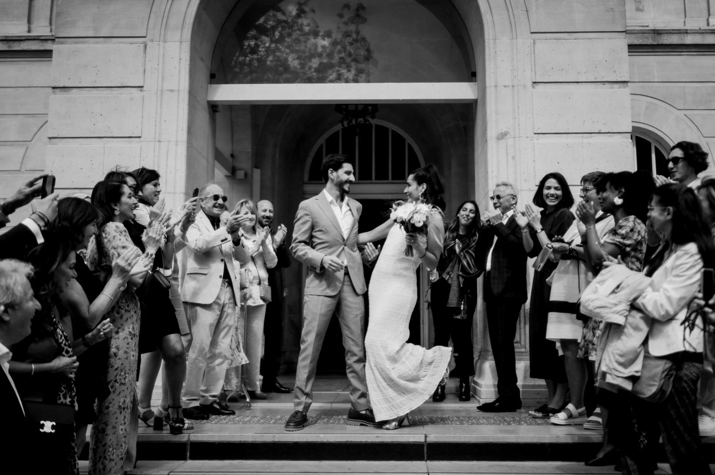 sortie-mariage-civil-mairie-couple-maries-applaudissements-noir-blanc-elopement-micro-wedding-small-intimate-wedding-photographe-mariage-film-mariage-the-wild-strawberry.webp