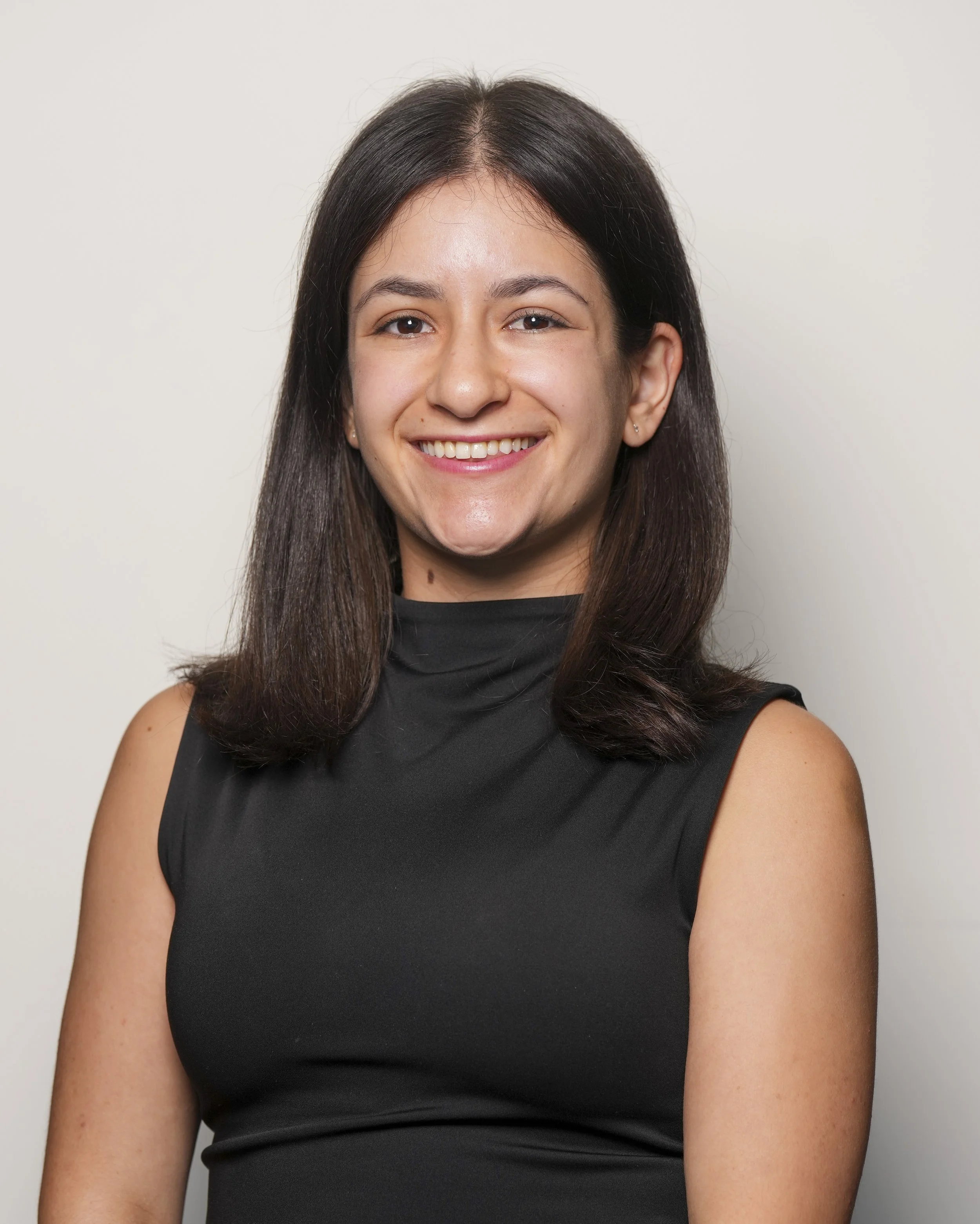 A young woman with dark brown hair, smiling, in a black shirt