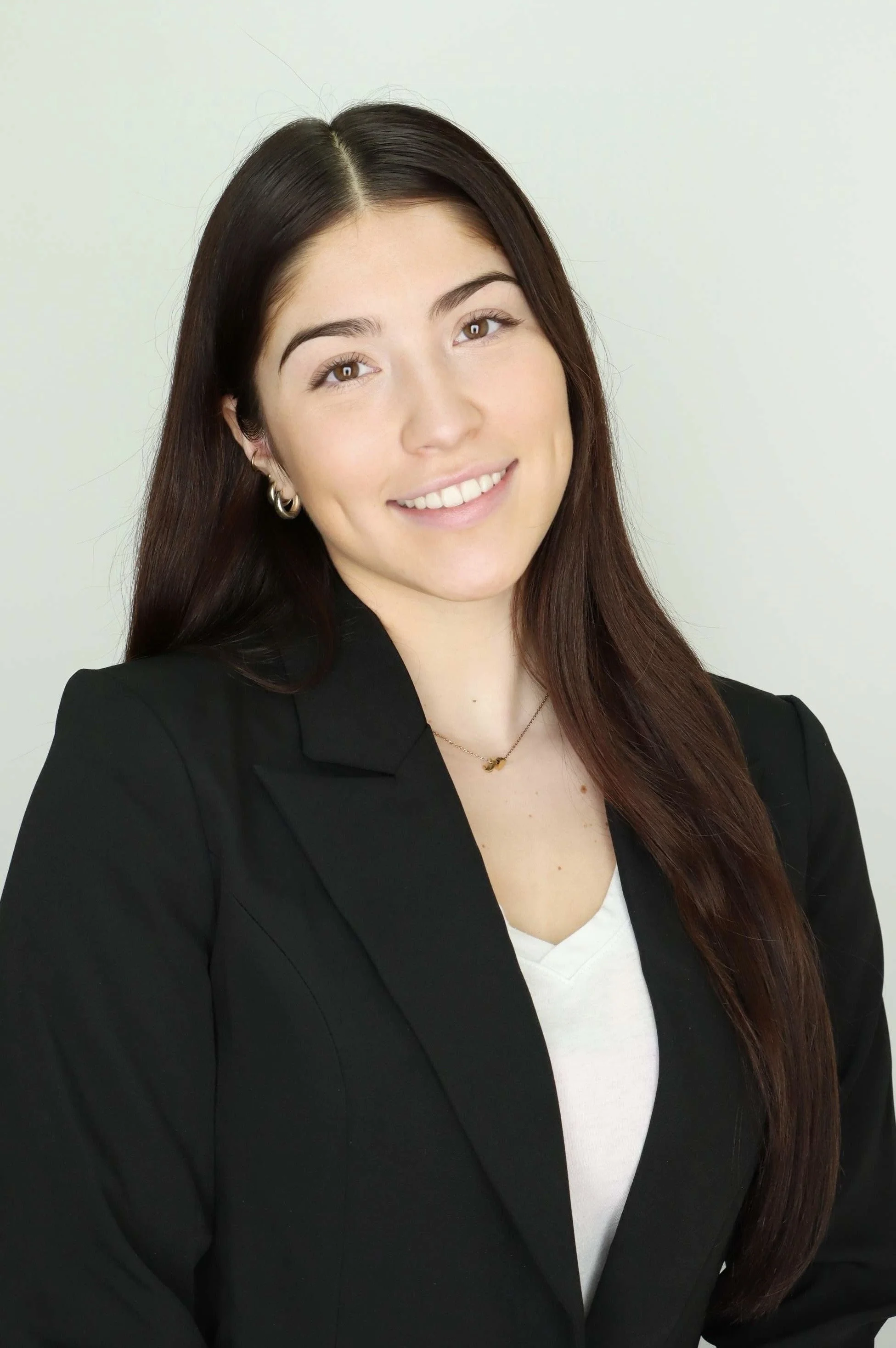 A young woman with long brown hair smiling in a professional headshot