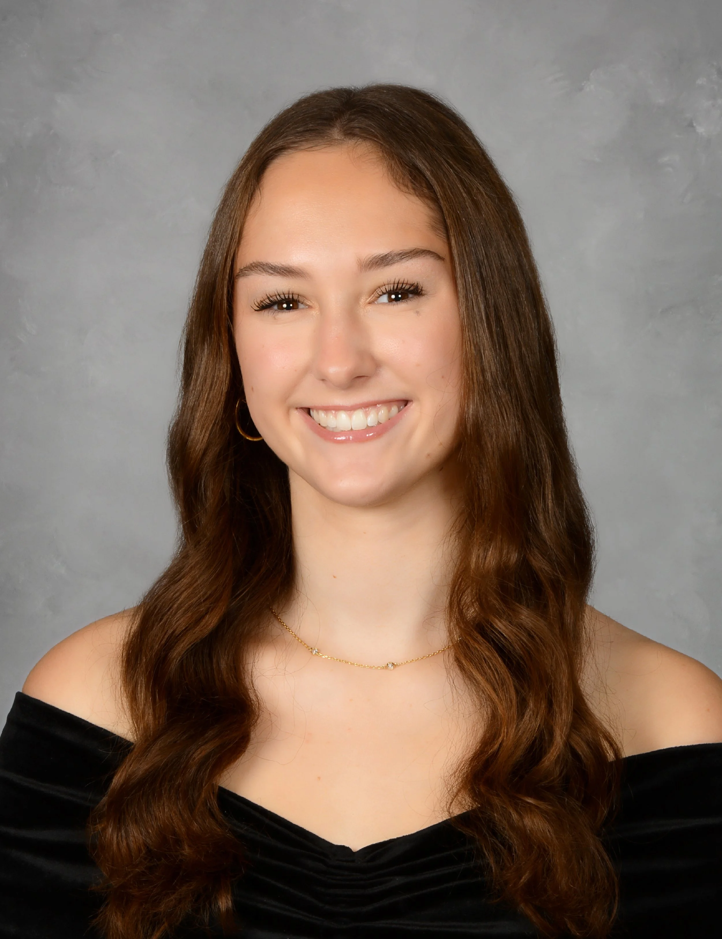 A portrait of a young woman with dark brown long hair, smiling