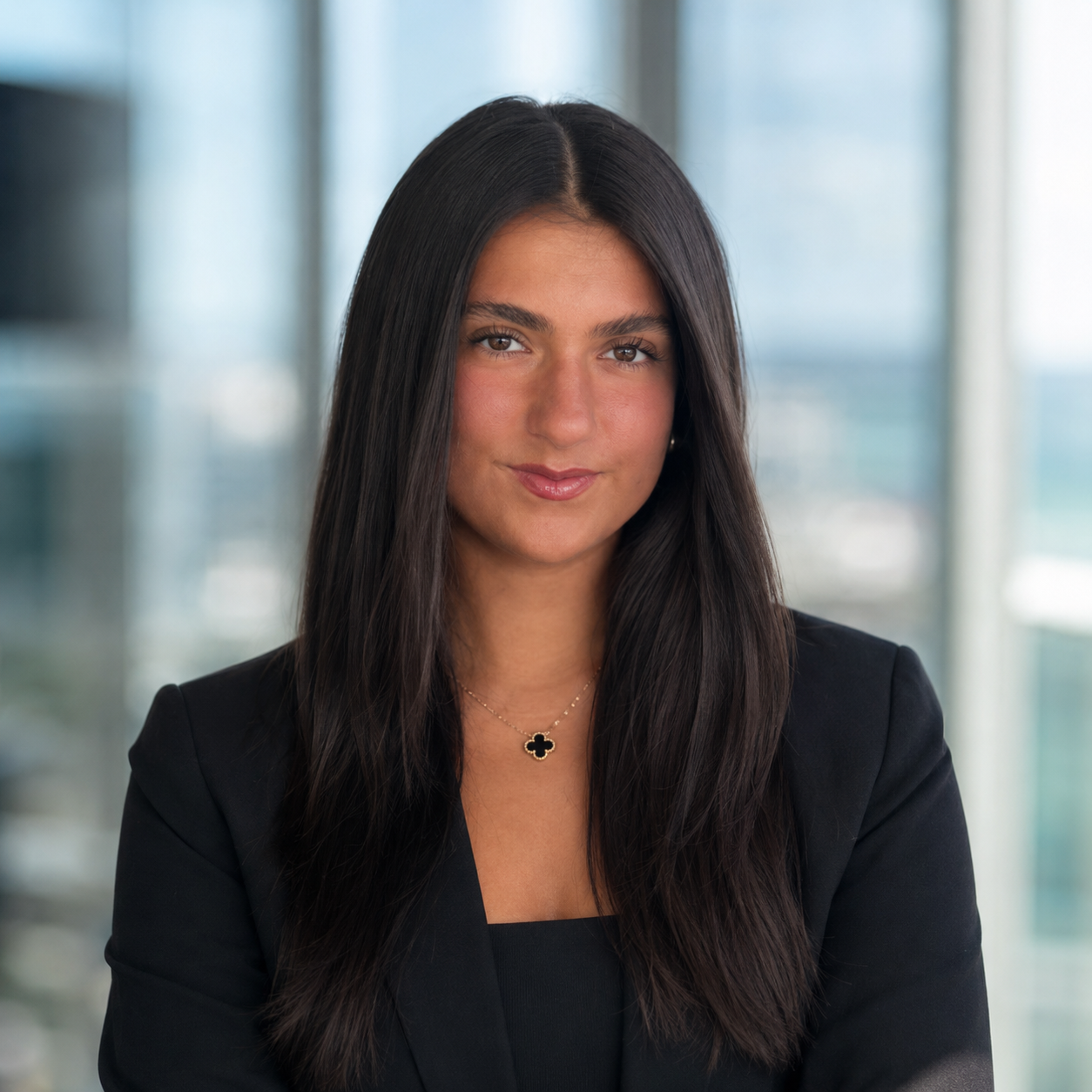 A young woman with long dark hair, smiling in a professional headshot wearing a dark blazer