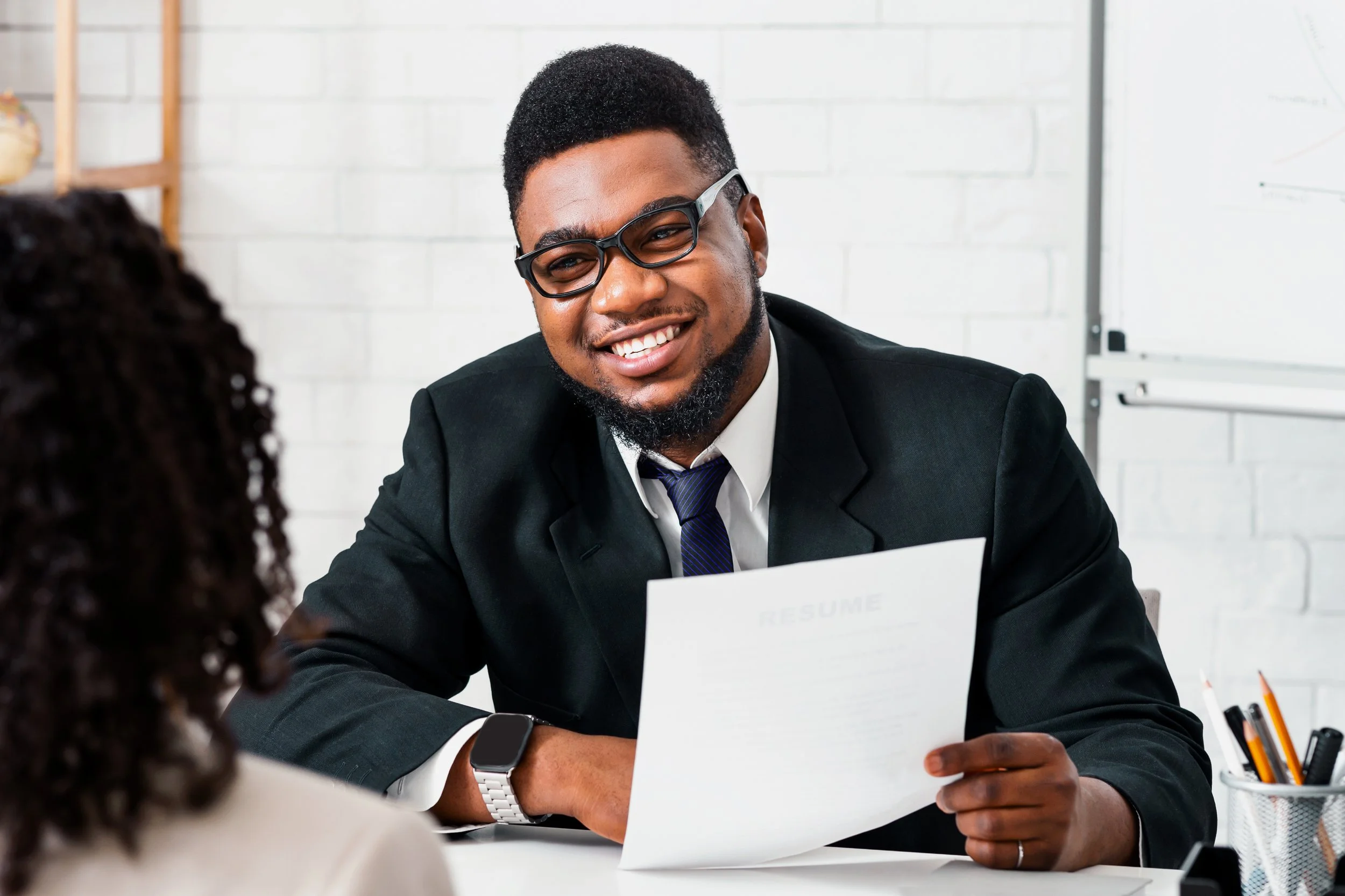 Male manager holding resume and smiling at female  candidate.