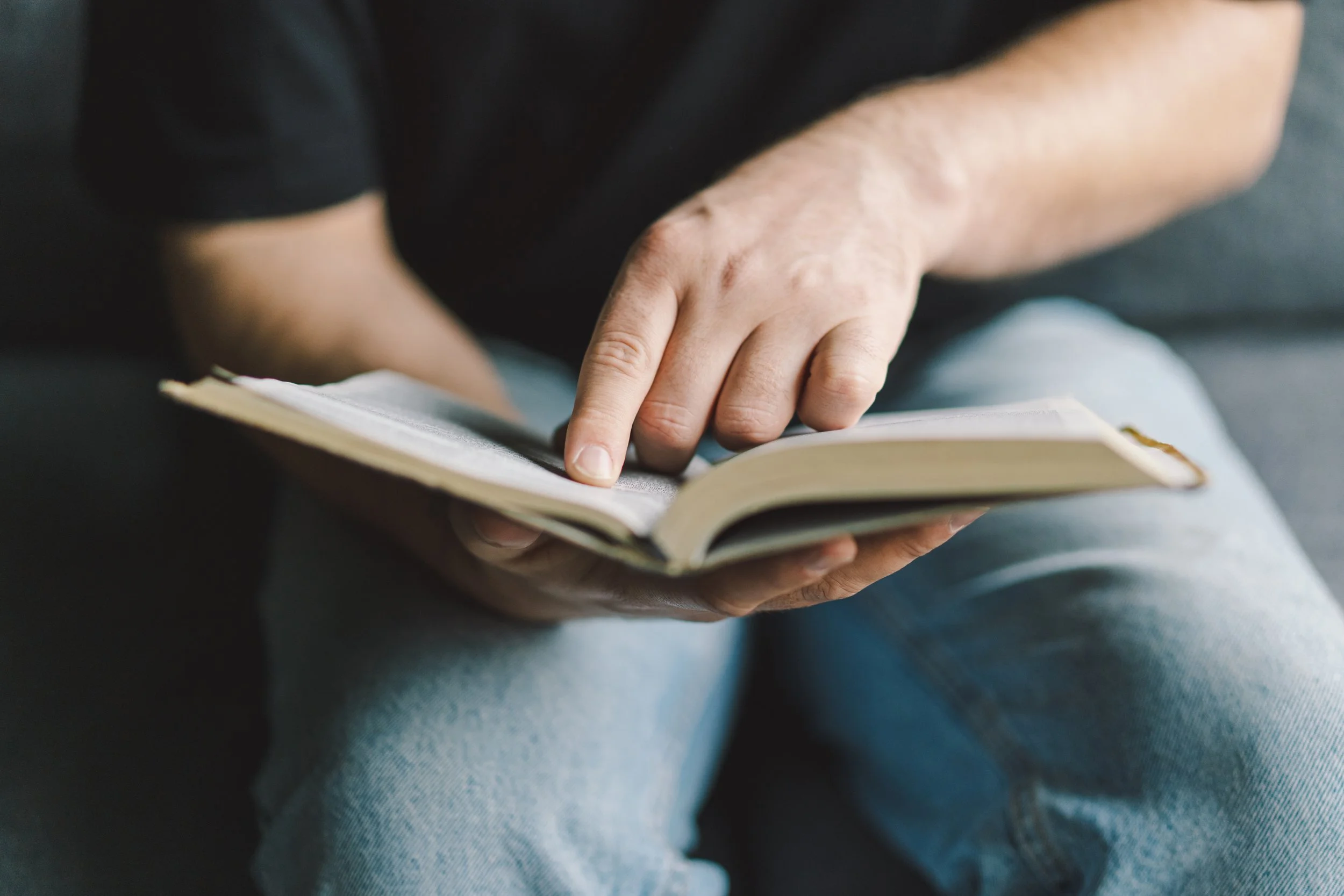 Person pointing at a page in a notebook, sitting casually.