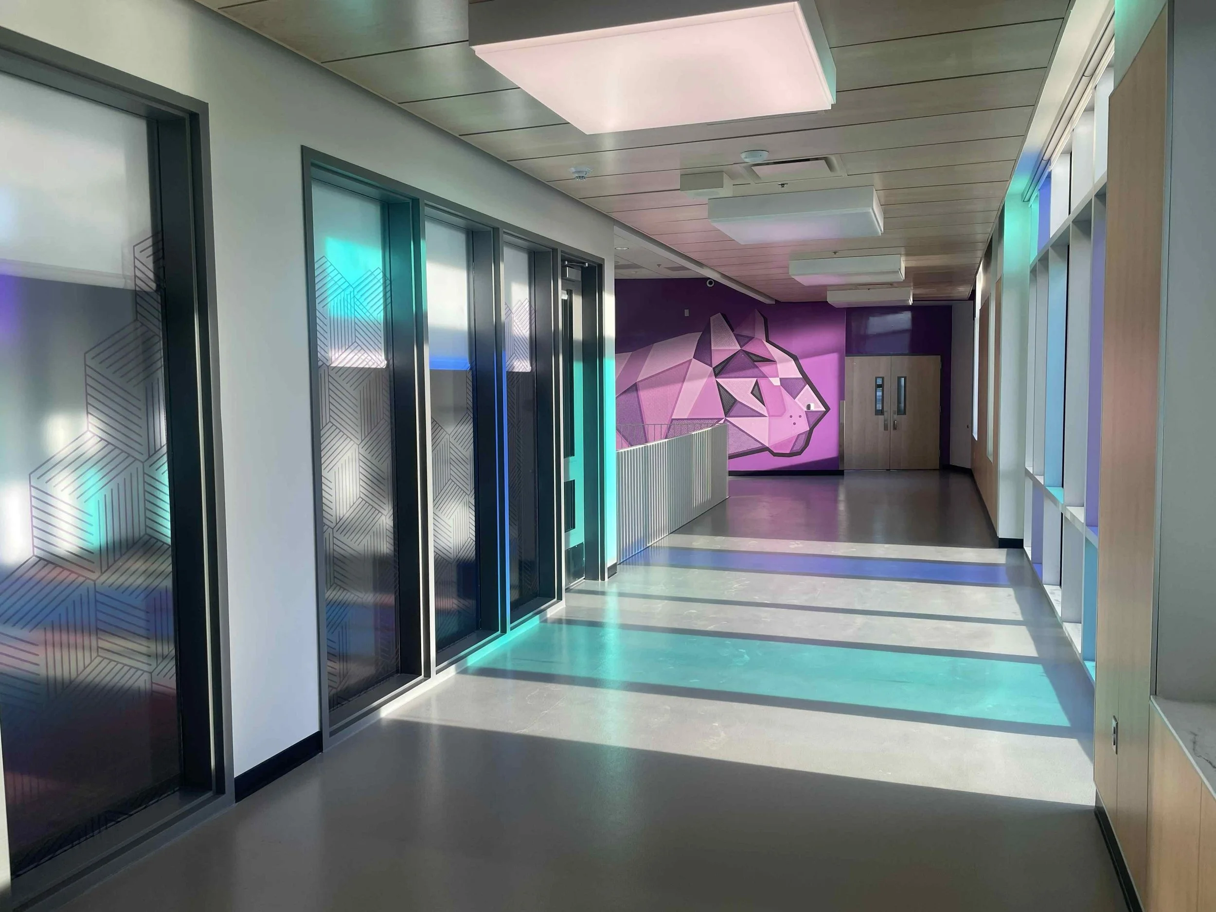 Modern indoor hallway with elevators on the left and colorful geometric wall art at the end of the corridor. Installed by Ascent Window Tint + Clearbra in Fort Collins, Colorado. NOCO