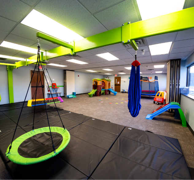 Gross motor gym with swings, slides, and mats at the MBS ABA Learning Center in Bloomington