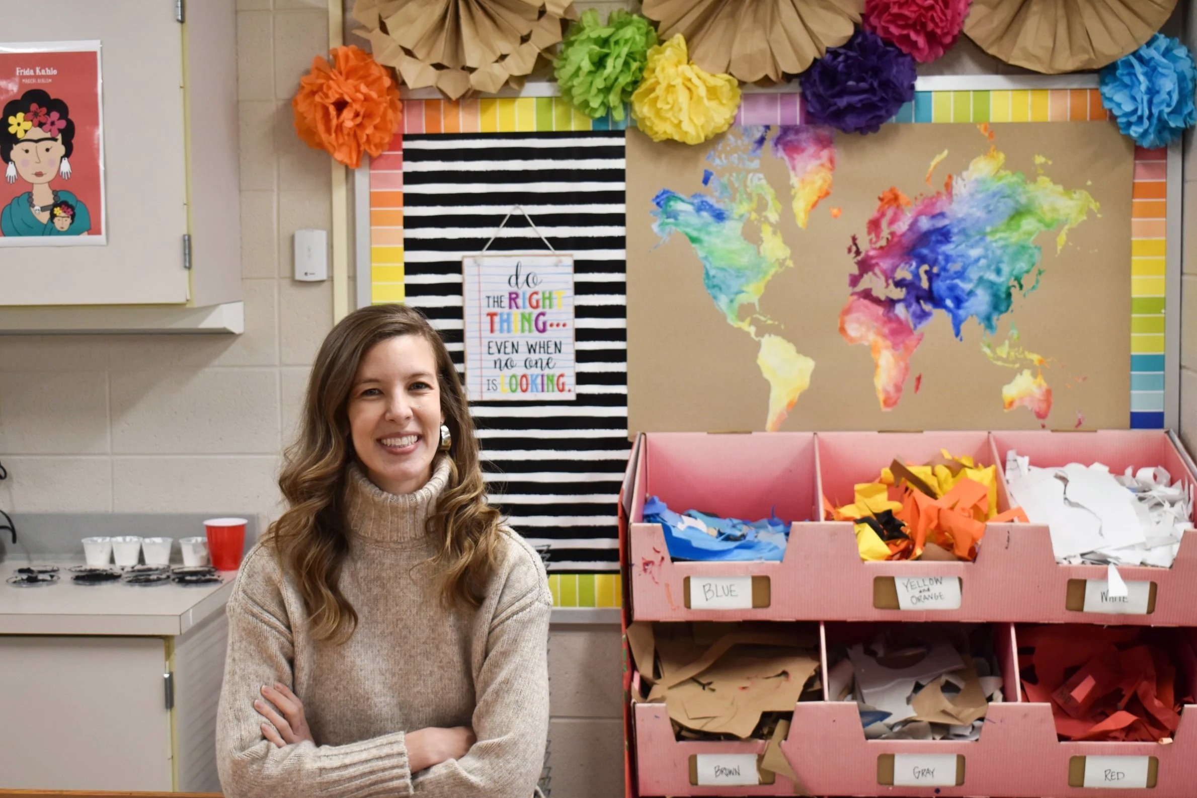 A smiling art teacher in a classroom.