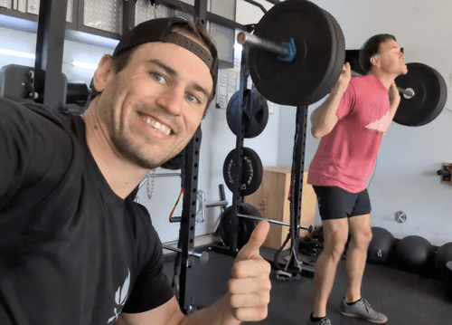 Sam Moses giving a thumbs-up while a client squats