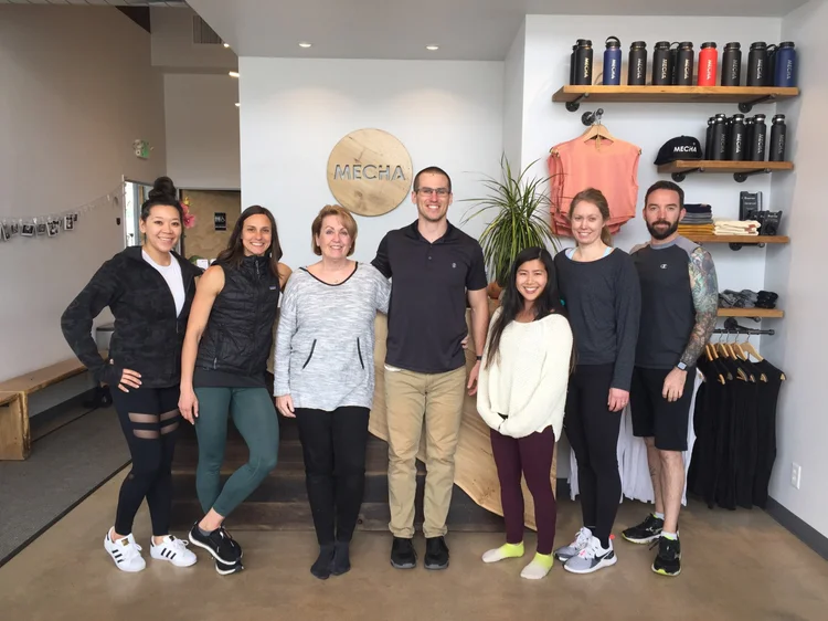 Sam Moses with a group of clients and coaches in a fitness shop