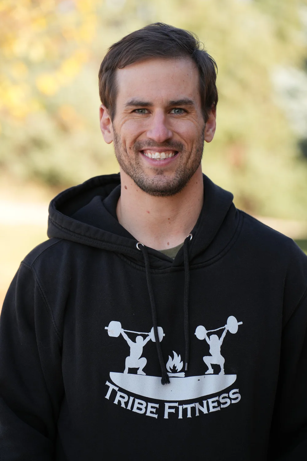 Sam Moses, founder of The Strong Parent Collective, smiling outdoors in a Tribe Fitness hoodie