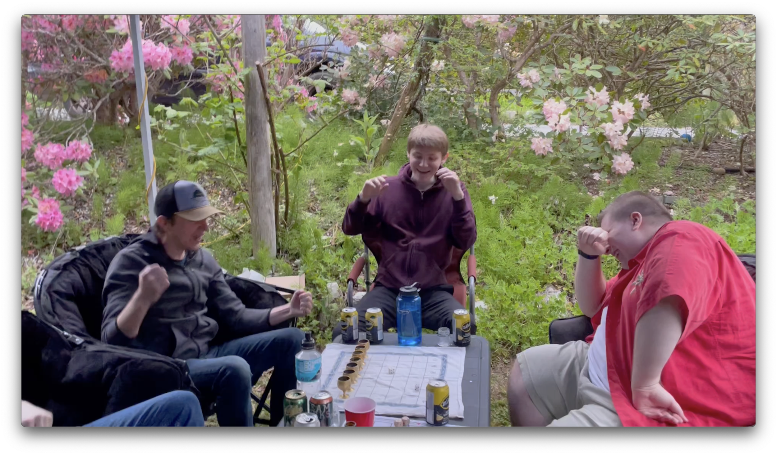 A Tablero Player pumps his fist in the air as he yells Set ‘em Up and Knock ‘em Down while his two friends laugh.