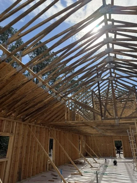 Construction site with wooden framing and roof supports, sunlight shining through the open roof structure. This is in St. John's County (Flagler Estates) and will end up being a nice custom home. This house is close to Putnam County and Palatka.