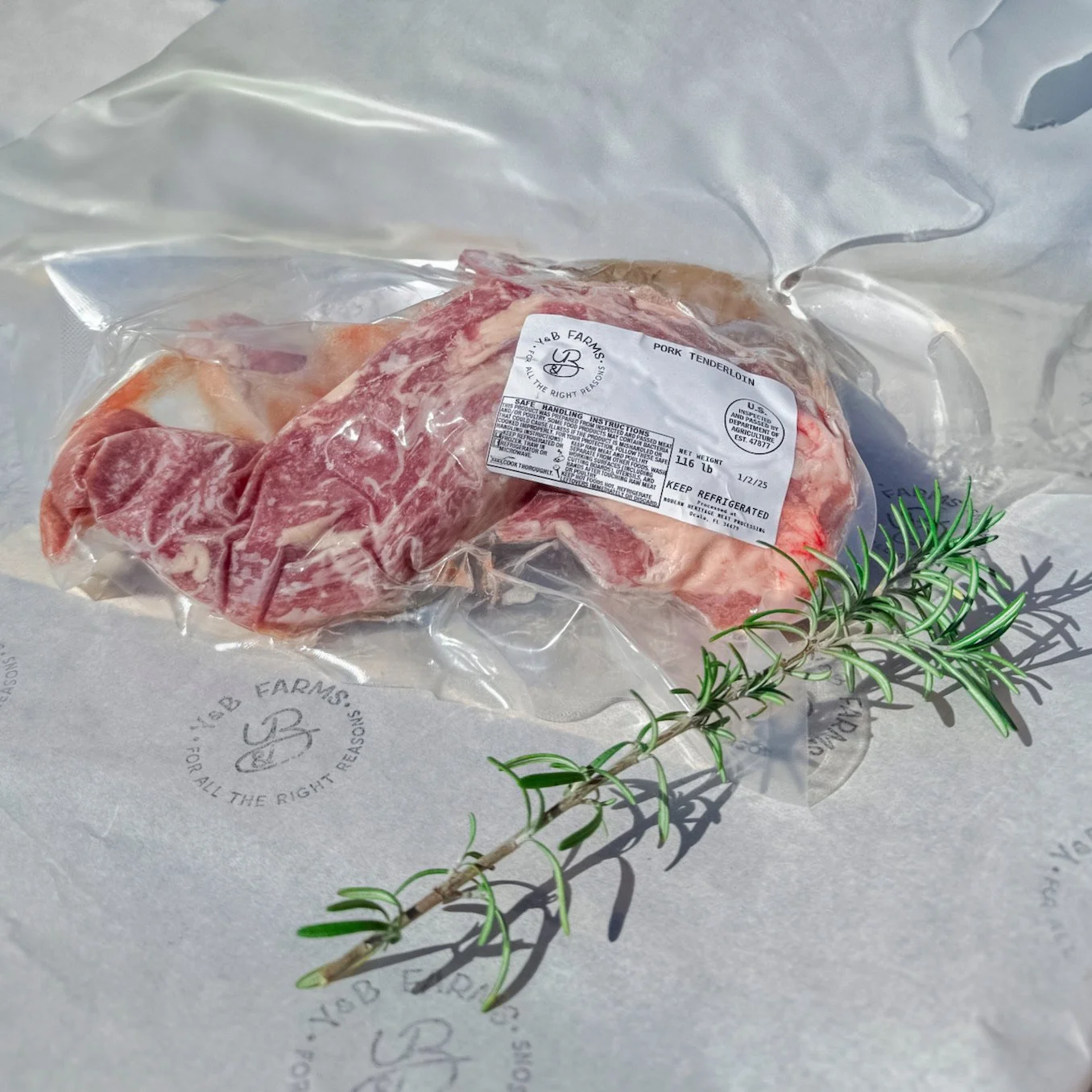 Vacuum sealed pork tenderloin on top of kitchen paper and a rosemary.