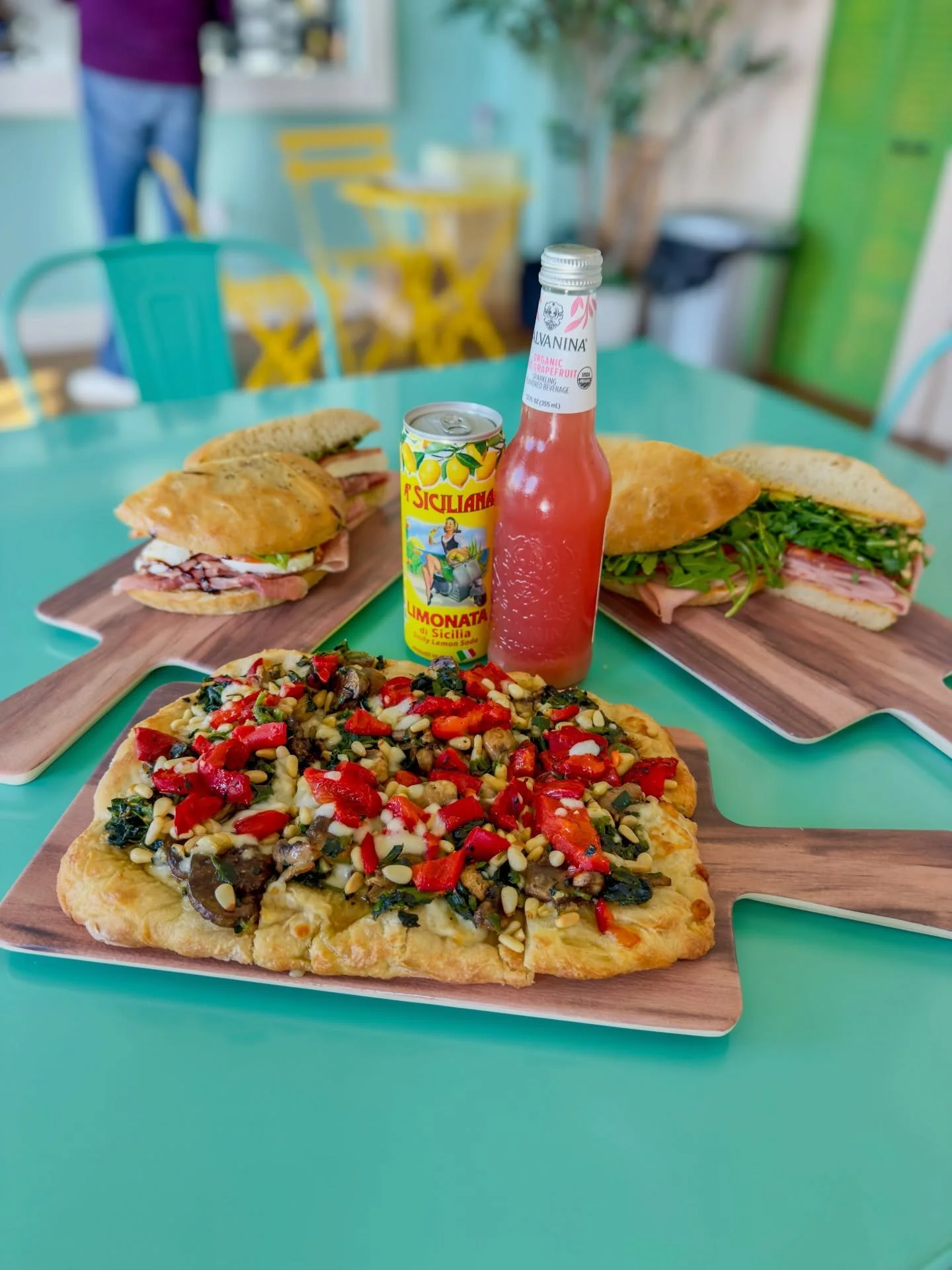 This is lunch at Buon Cibo.
Golden, crispy pinsa loaded with roasted mushrooms, fire-roasted red peppers, wilted spinach, and toasted pine nuts over melted Fontina. Two overstuffed Italian sandwiches on handcrafted bread. A cold Sicilian limonata to 