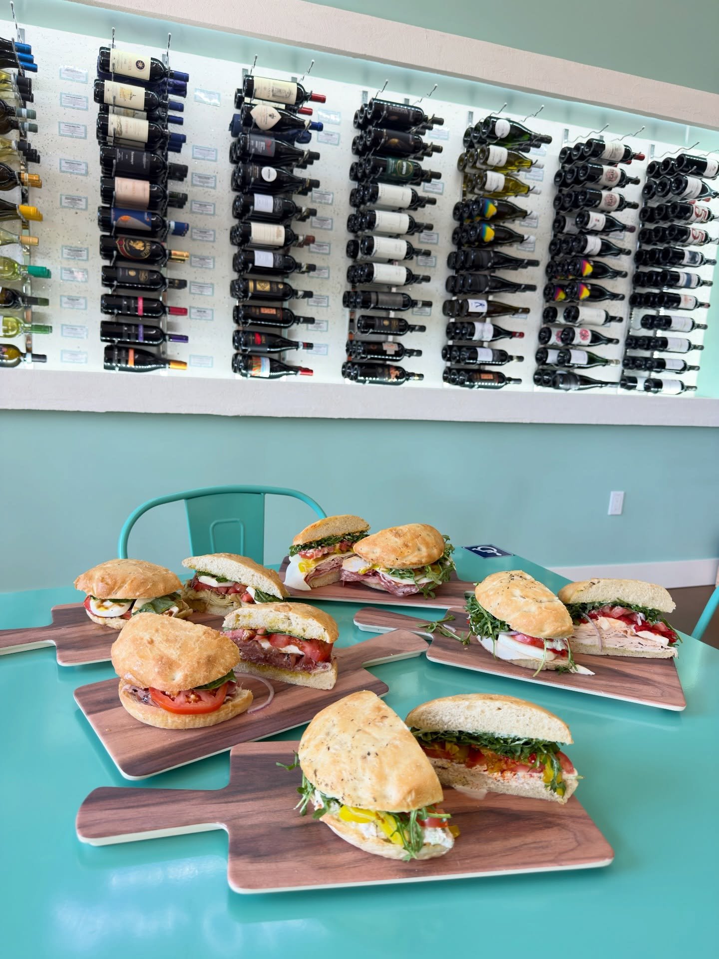 This is what lunch looks like at Buon Cibo.

A table full of handcrafted sandwiches, 102 hand-picked wines on the wall behind you, and the quiet hum of neighbors doing lunch right. There is something we love about watching a table fill up in the midd