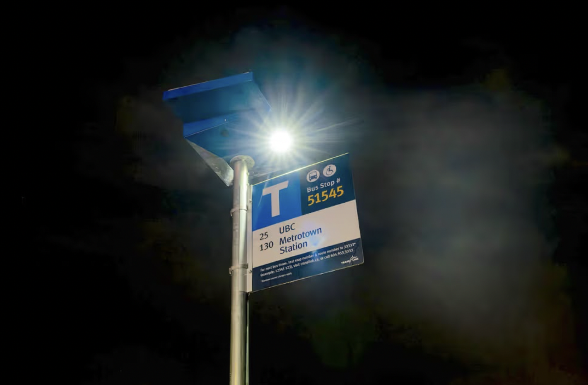 A solar lighting unit shines bright in the darkness illuminating a bus stop in Vancouver, BC