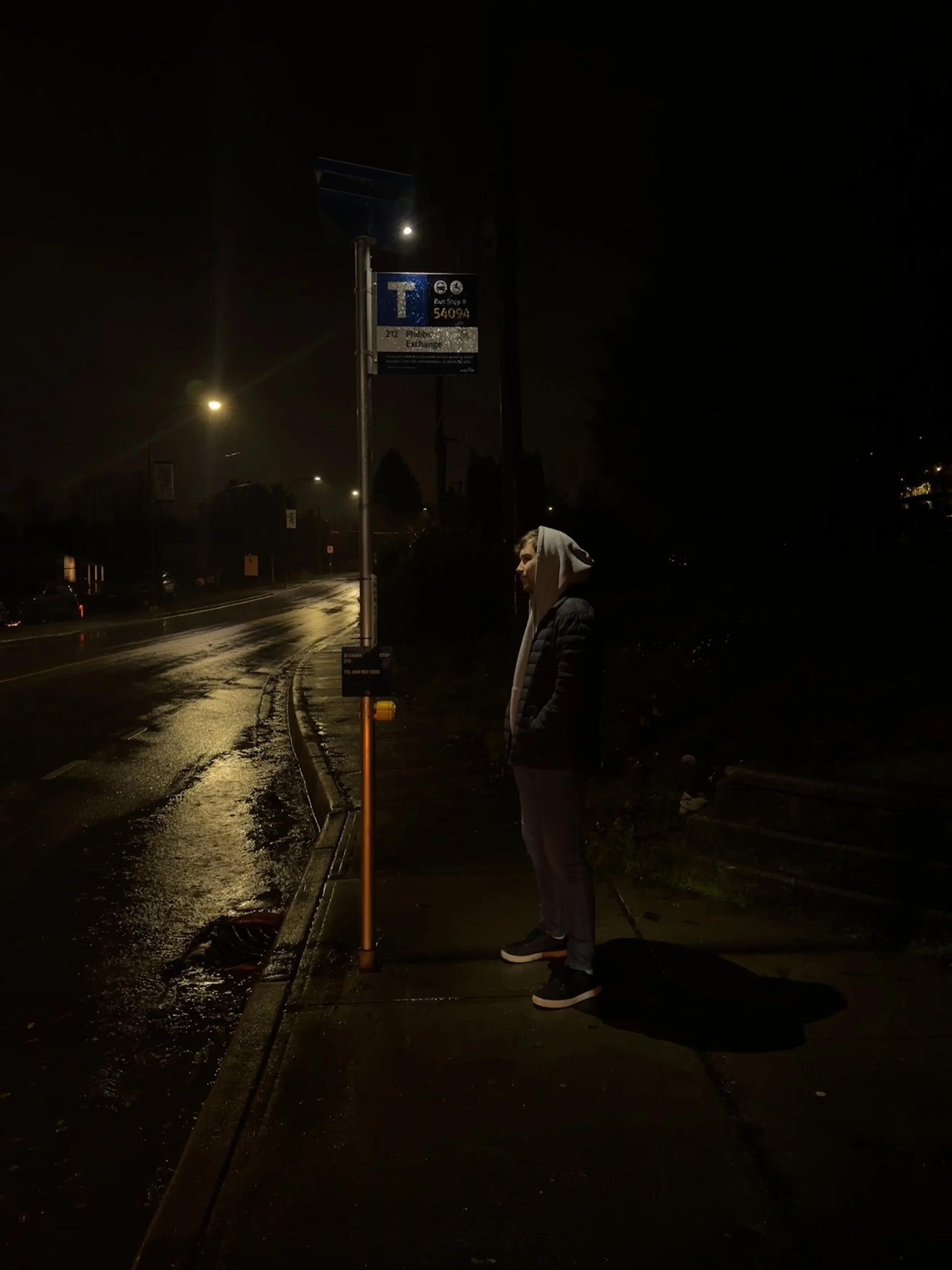 A male passenger is illuminated a bus stop by Urban Solar's solar-powered transit security lighting