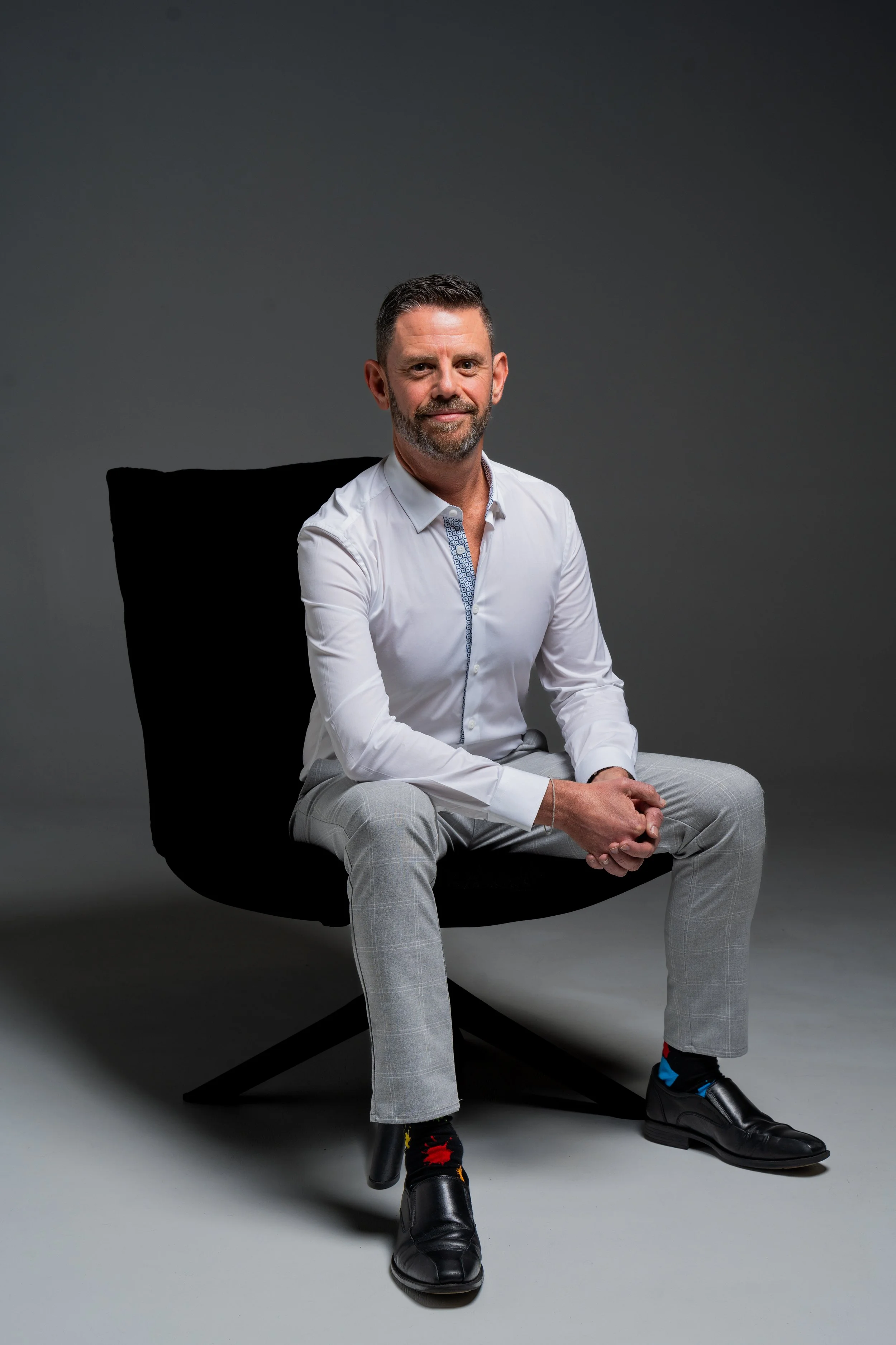 Man sitting on a chair wearing a white shirt facing the camera.