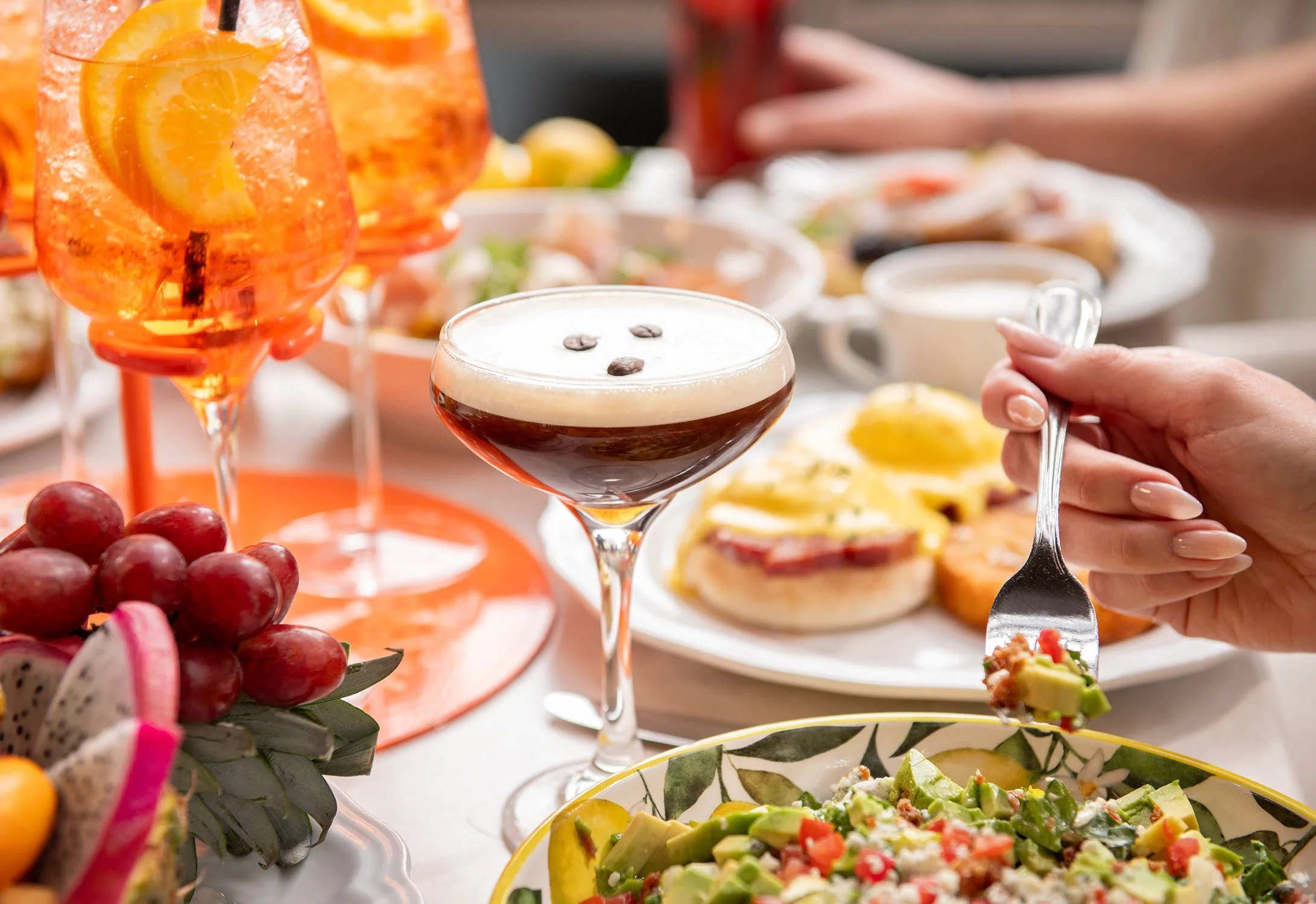 A table with various foods and drinks, including salads, desserts, fruit, and cocktails, at Cheri Rooftop during brunch.