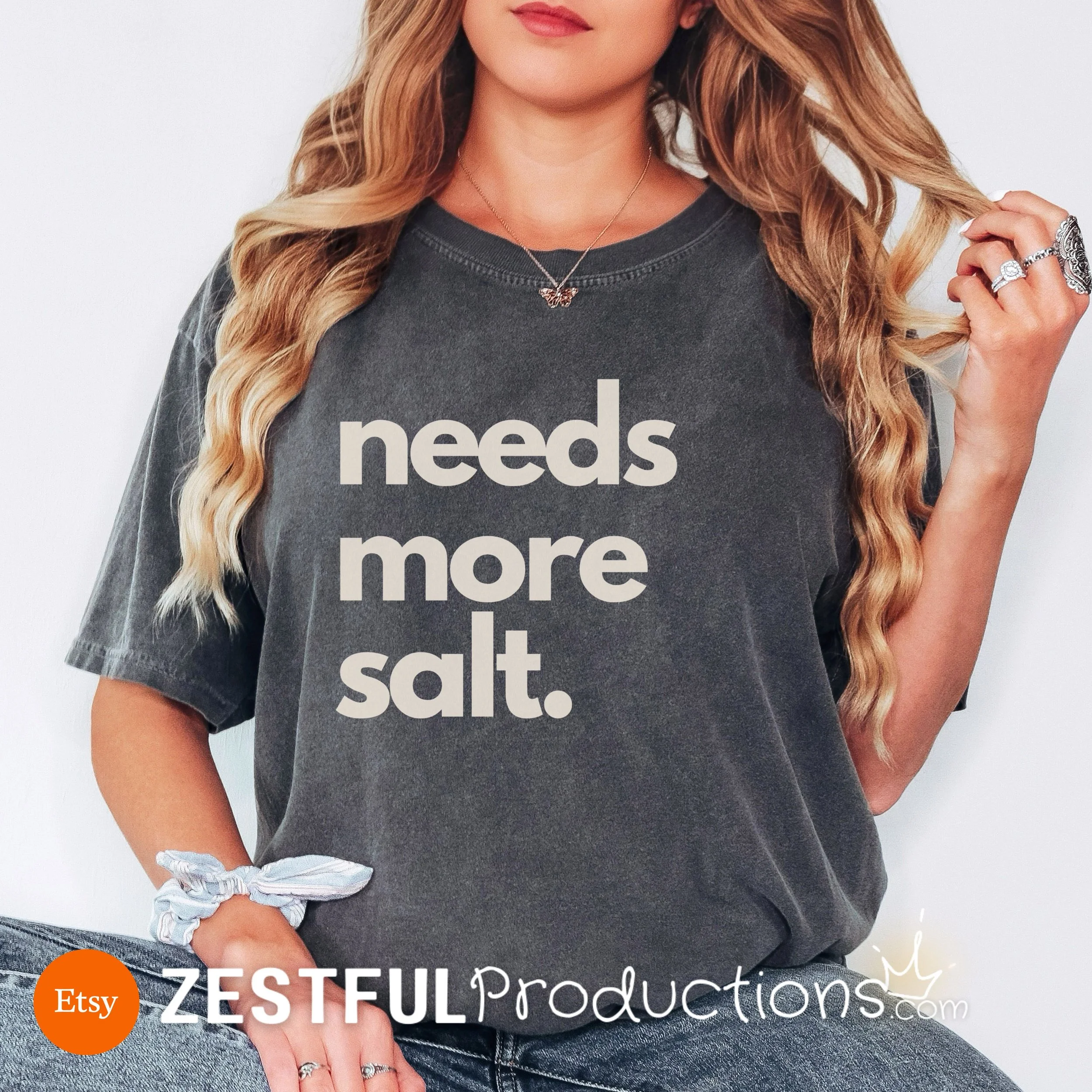 Charcoal gray garment-dyed t-shirt with cream 'Needs More Salt' design – relaxed unisex culinary graphic tee.