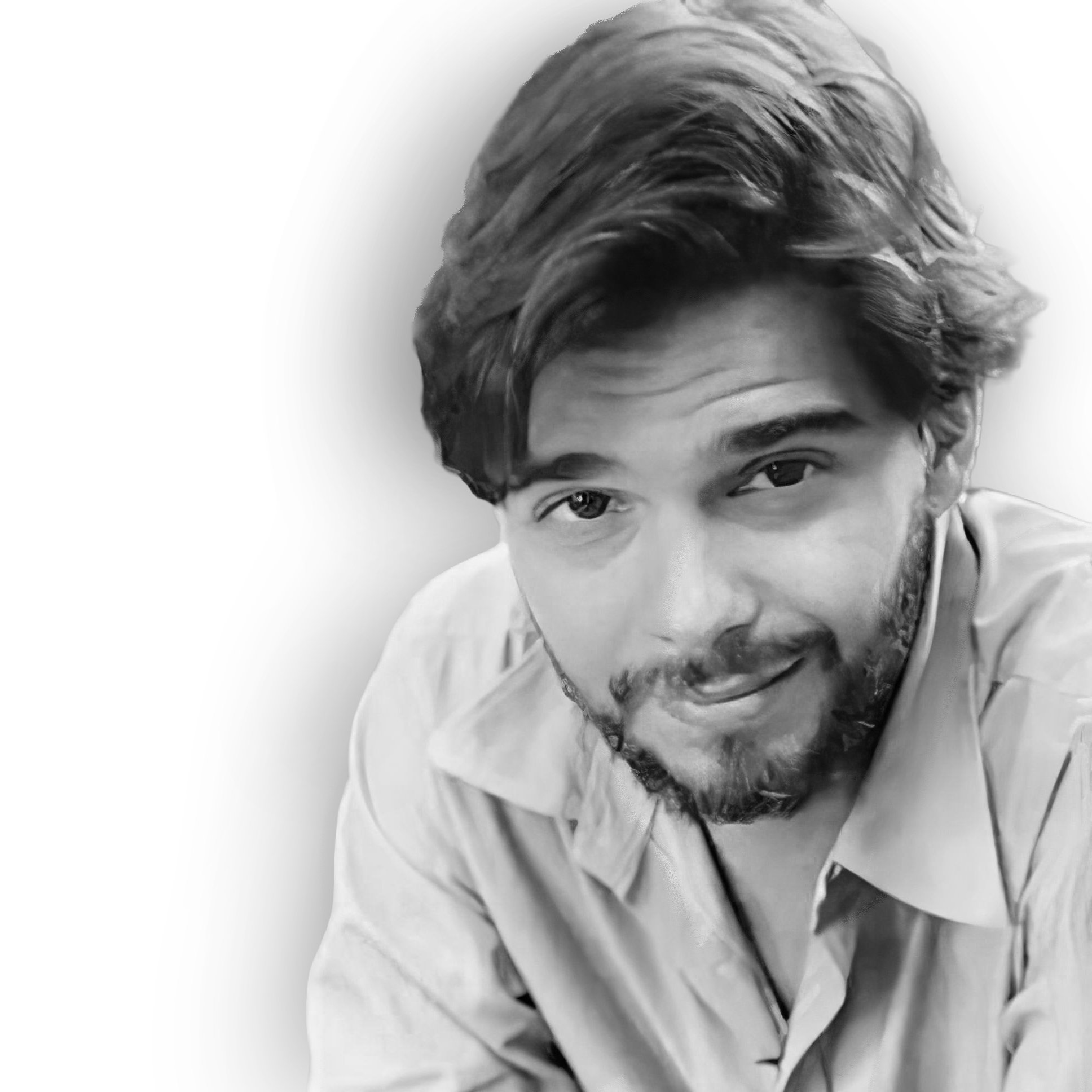 Black and white close-up portrait of a young man with wavy hair and facial hair, smiling and looking at the camera.