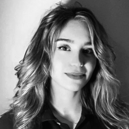 Black and white photo of a woman with wavy hair, smiling slightly, wearing a dark top.
