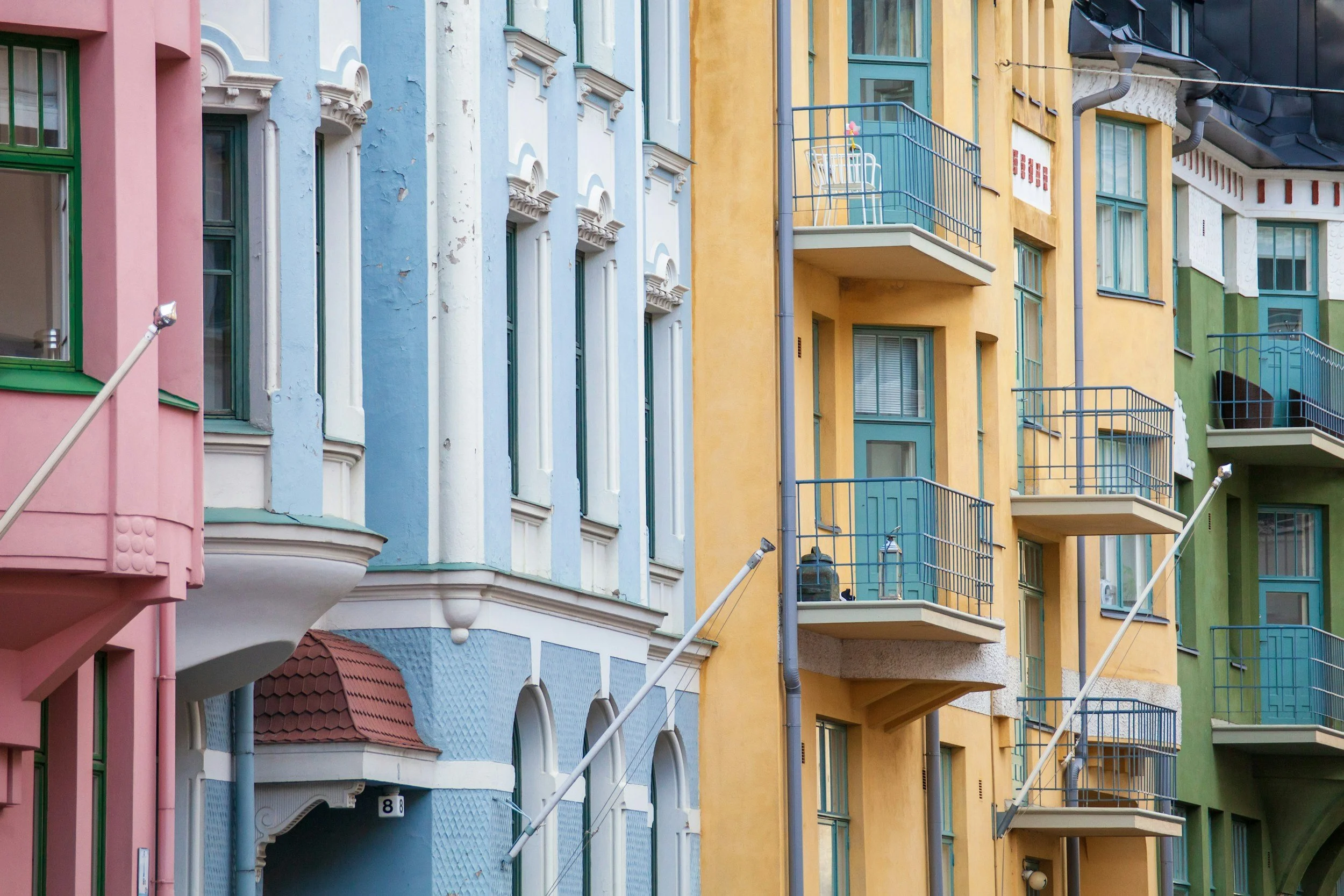 Colorful apartment building facades in pink, blue, yellow, and green with windows, balconies, and exterior details.