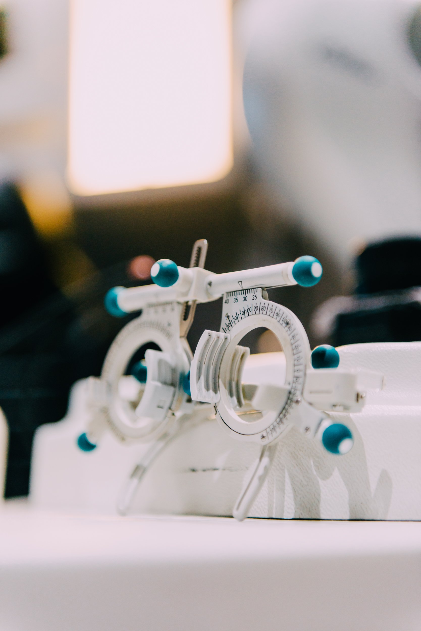 A phoropter with white and blue adjustment knobs used for eye examinations.