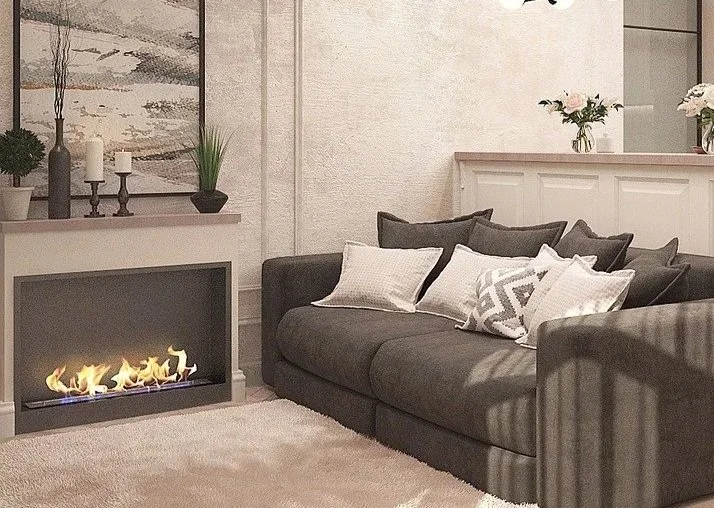A cozy living room with a dark gray sofa, decorative pillows, a modern fireplace, potted plants, candles, and floral arrangements.