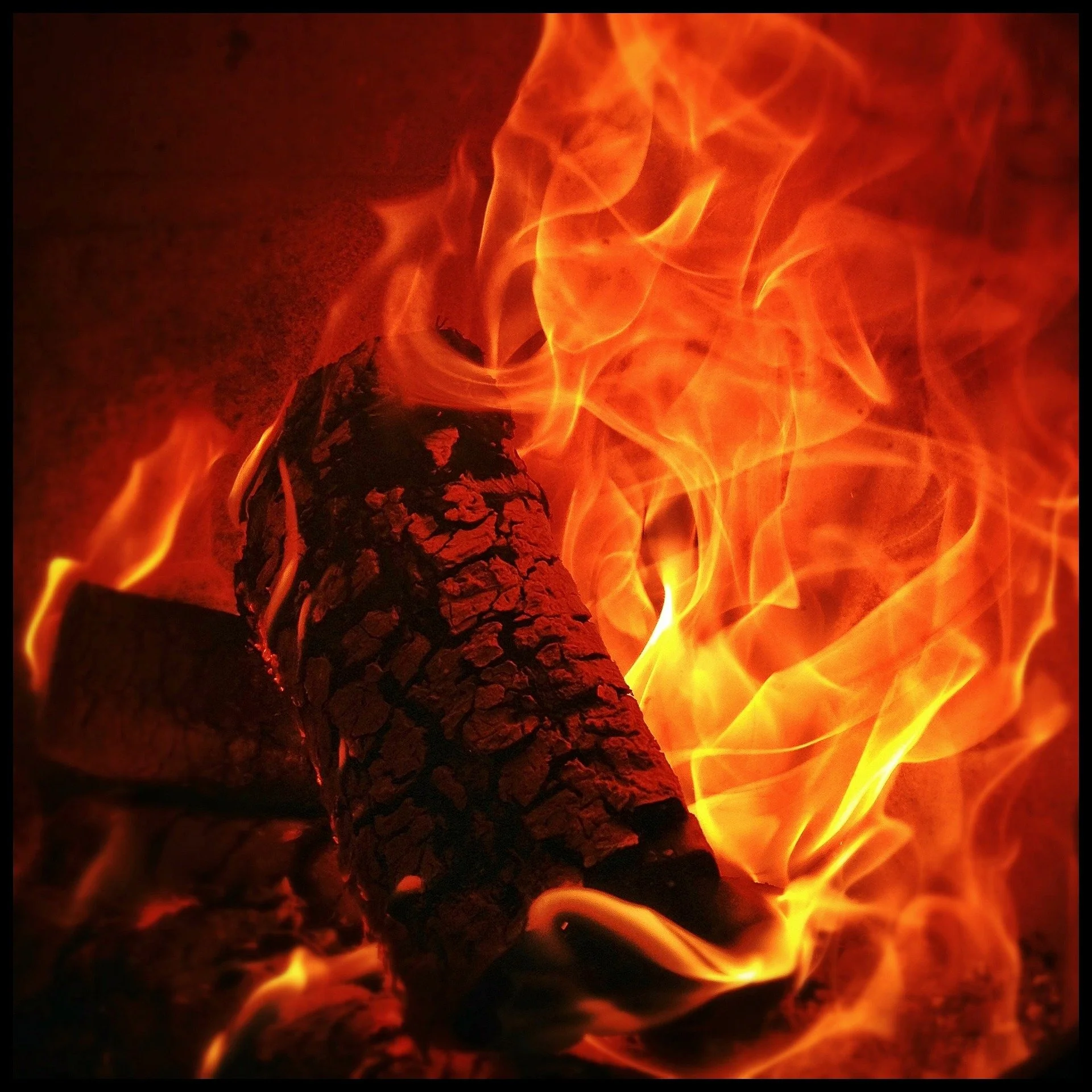 Close-up of burning logs with orange flames surrounding them.