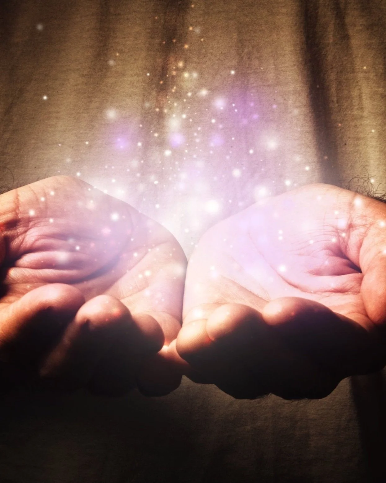Open hands cupped together holding a soft, glowing light with spark-like particles rising upward, symbolizing Intentional Living, inner awareness, and collective growth within the Conscious Evolution Experience.