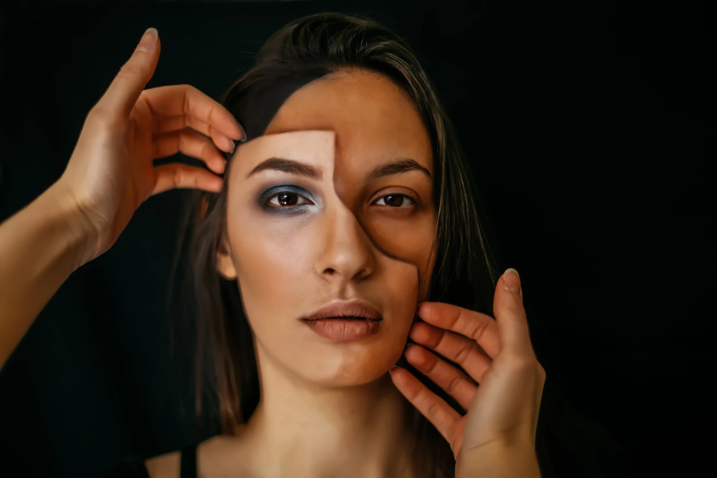 Portrait of a woman facing forward as hands adjust a half-face overlay, symbolizing identity, perception, and inner transformation. Used on Conscious Evolution Dialogues to represent foundational Conscious Evolution experiences.