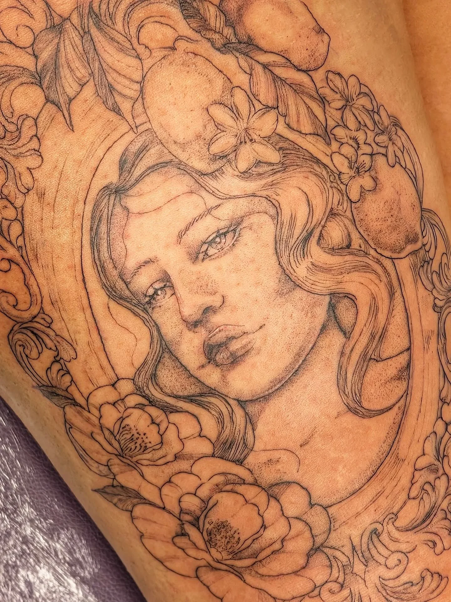 A tattoo design of a woman's face surrounded by flowers and decorative elements.