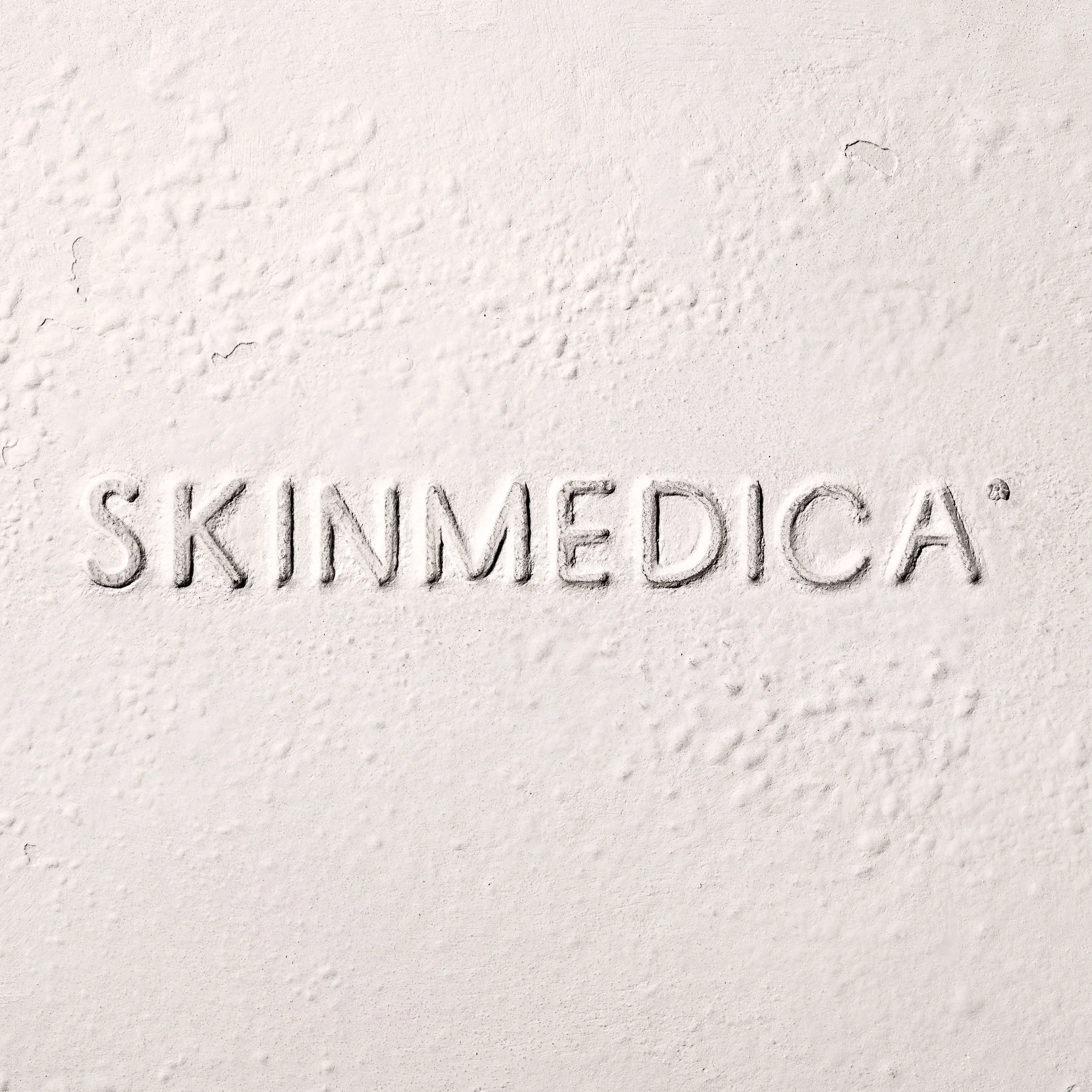 The word 'SKINMEDICA' embossed in the sand.