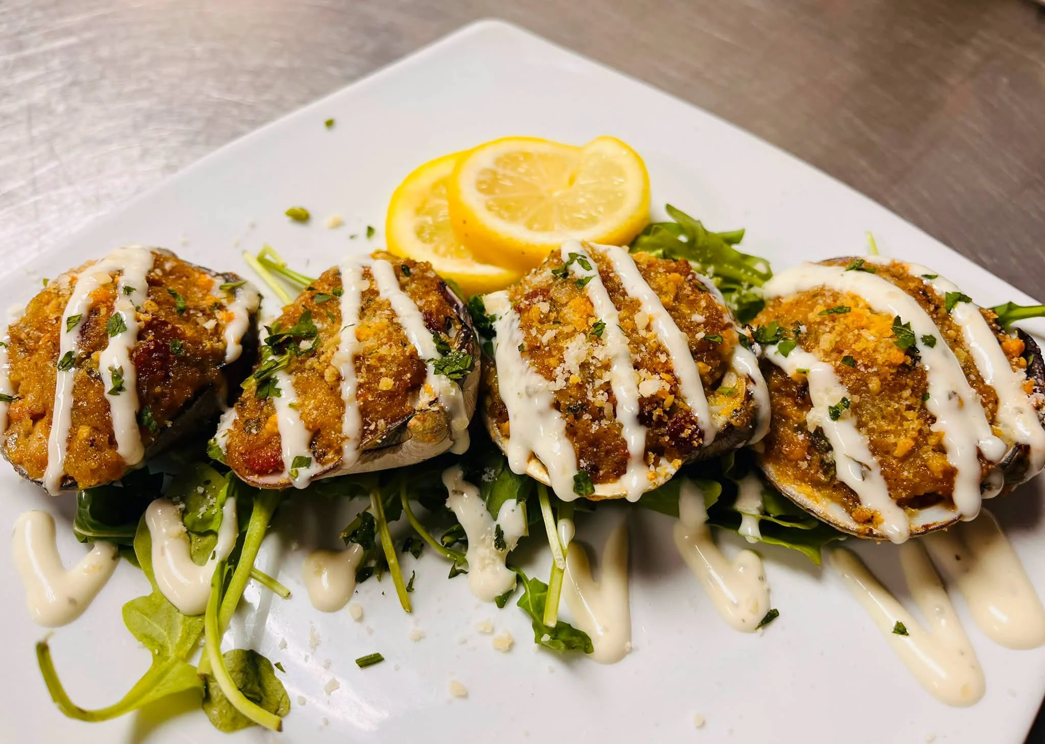 Breaded and baked stuffed mushrooms drizzled with white sauce, served on a bed of salad greens with lemon slices.