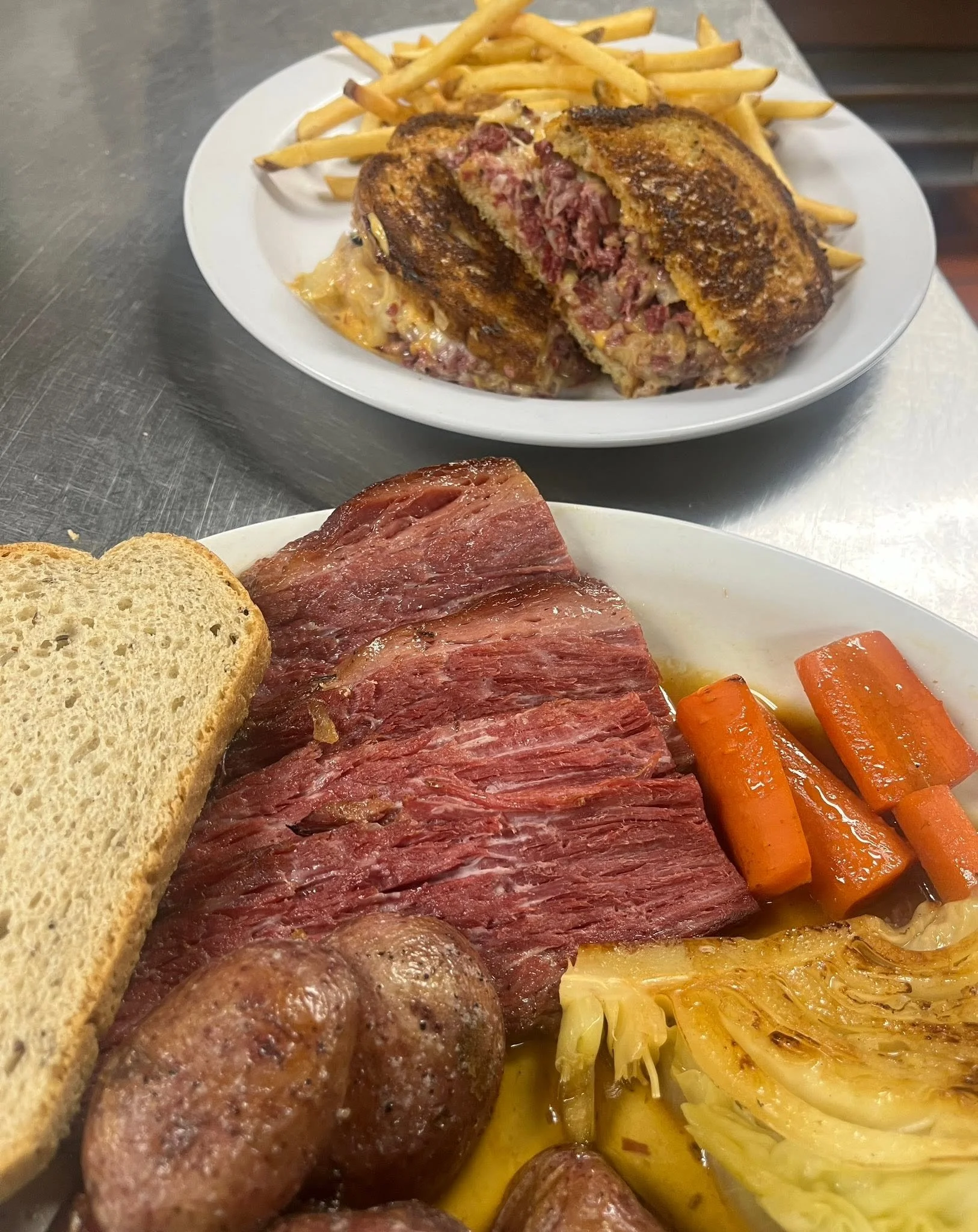 Plate of cooked meats, sliced bread, roasted carrots, and sautéed cabbage