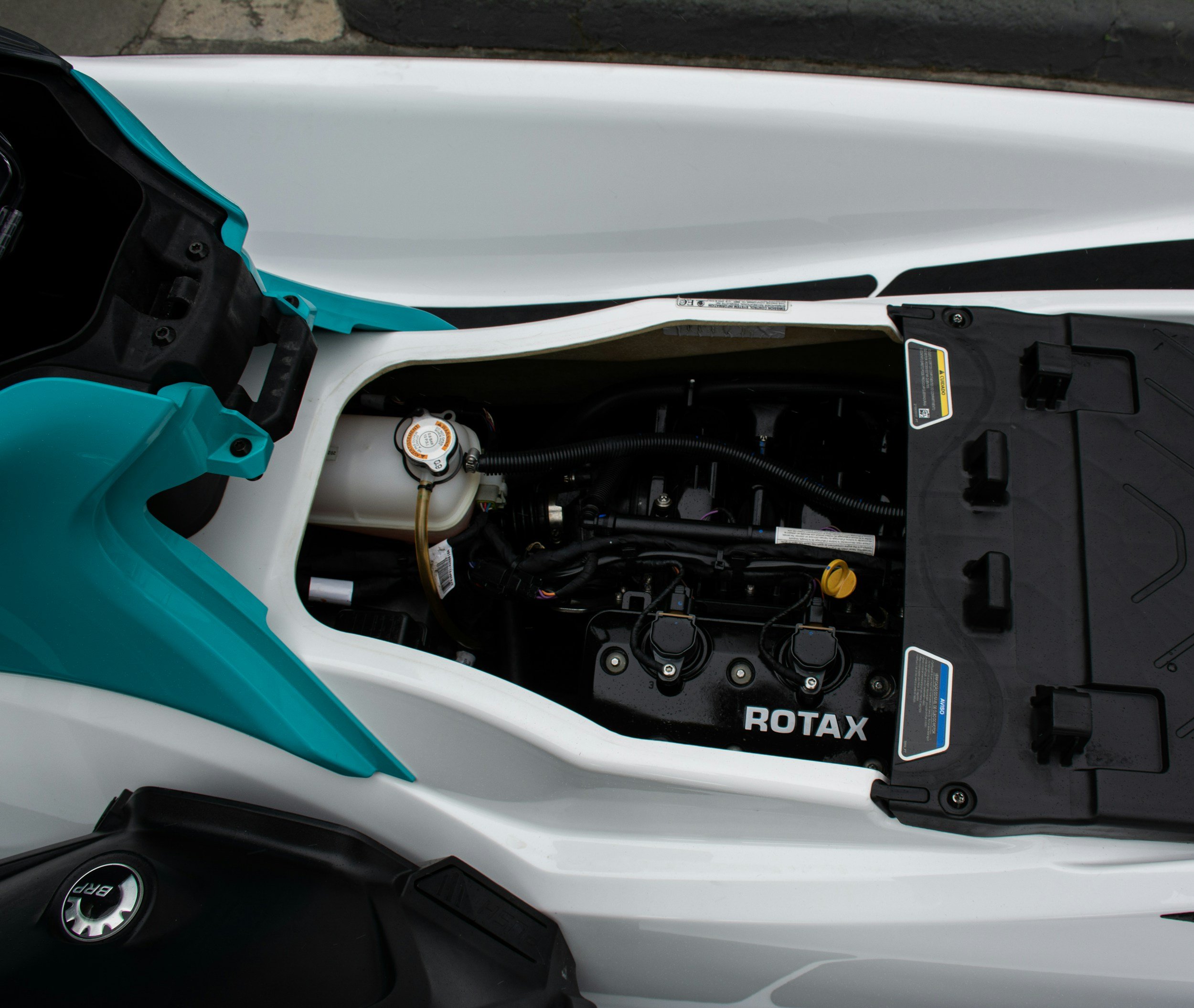 Close-up of a electric vehicle motor with visible wires, labels, and components, part of a teal and white watercraft rotax vehicle.