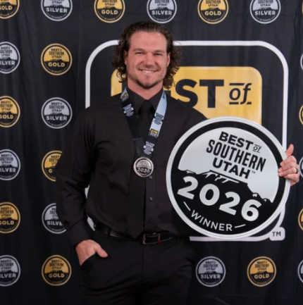 Man smiling and holding a circular award sign that says 'Best of Southern Utah 2026 Winner' at an awards event.