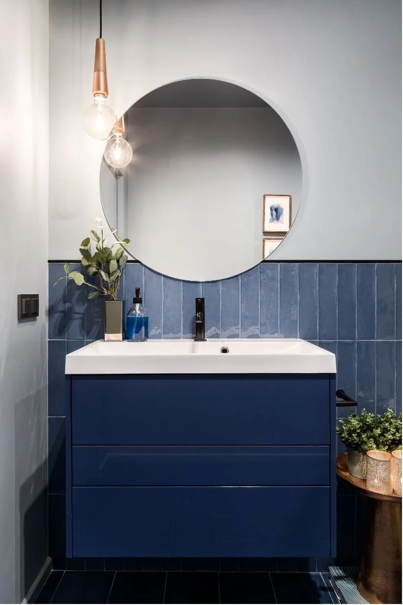 Blue bathroom remodel idea for 2025 with vertical tiles and a modern blue vanity with black fixtures.