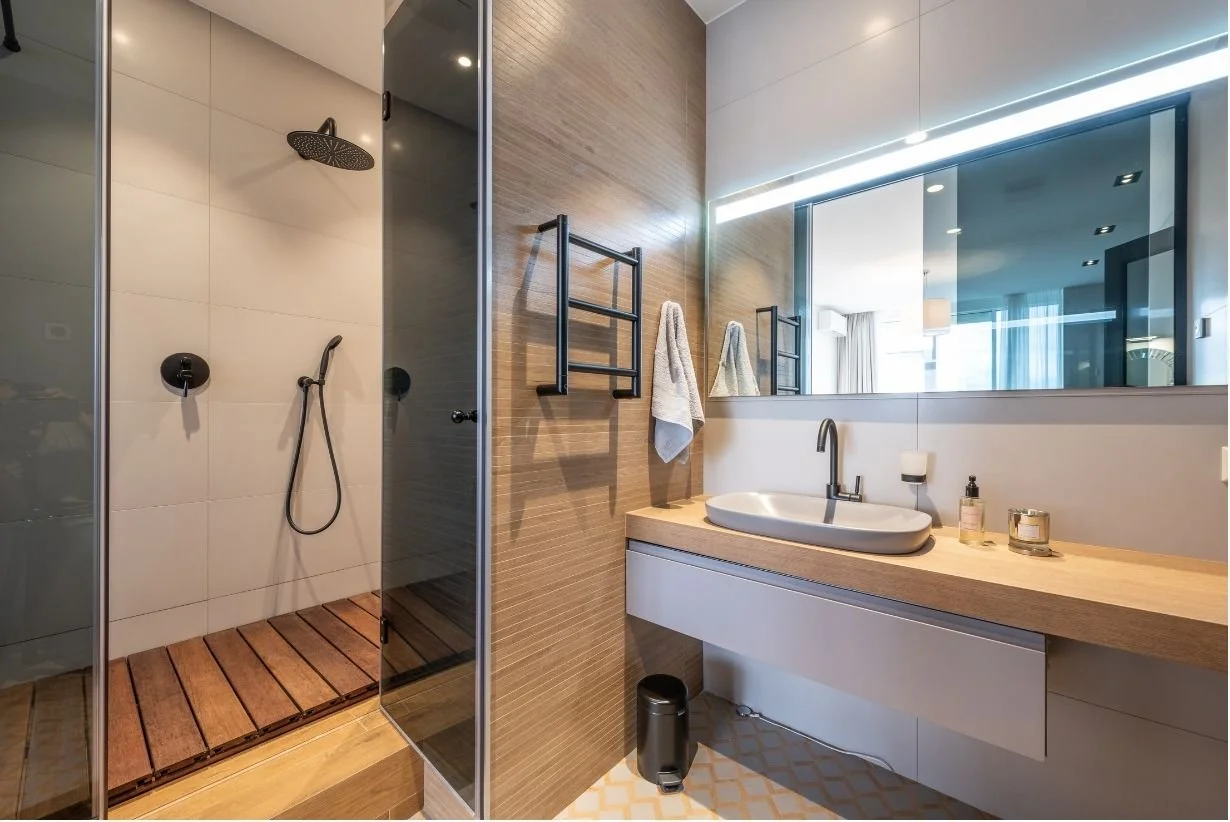 Modern luxury bathroom remodel idea for 2025 with wooden accents and stone gray colors.