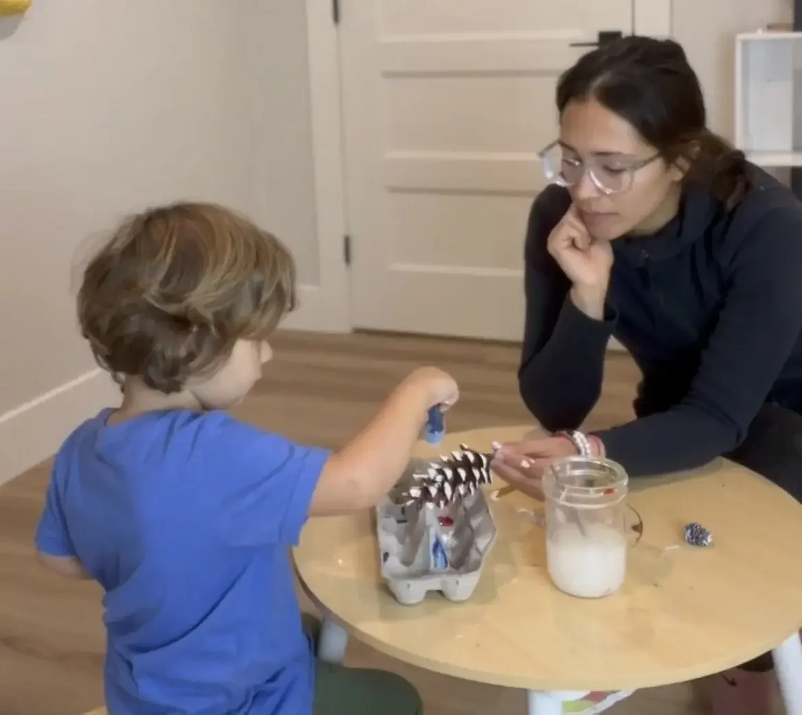ABA therapist supporting a child through a hands-on learning exercise to develop fine motor and communication skills.