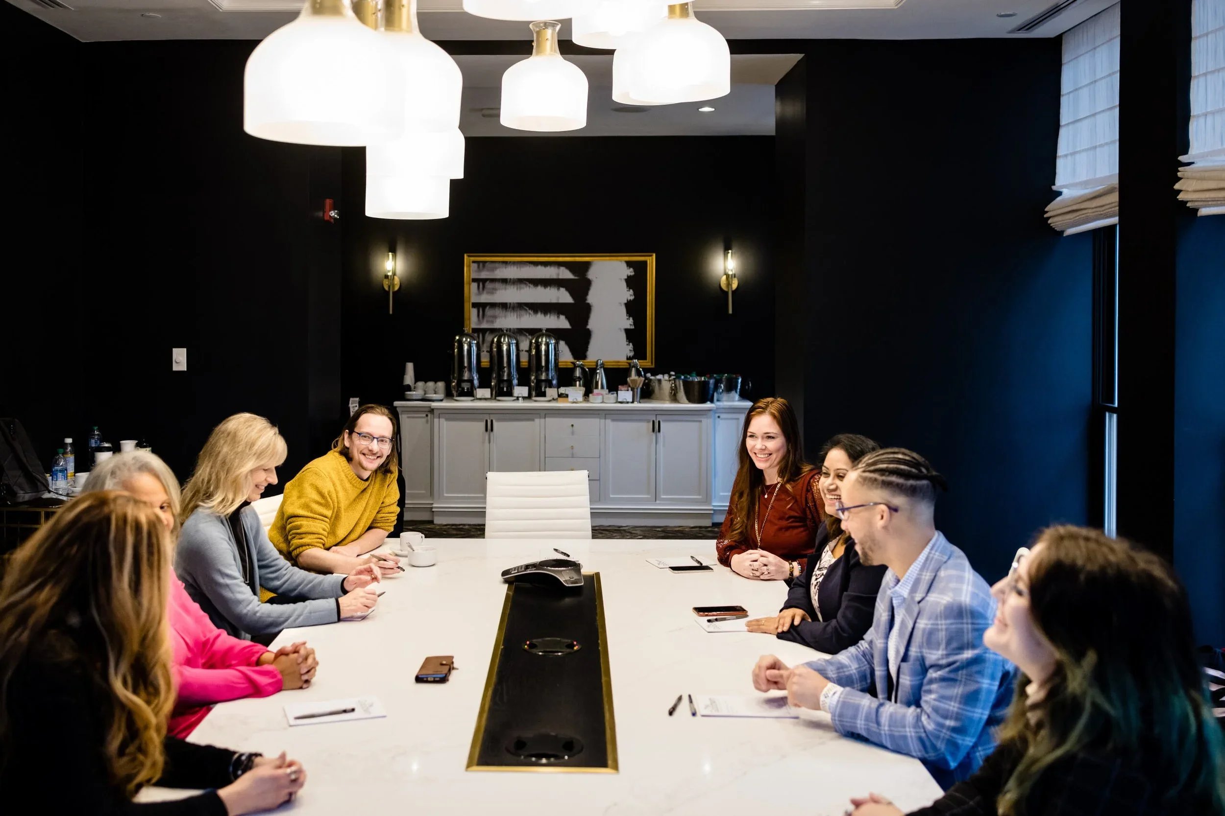 People sitting around a conference table in a modern meeting room, laughing and having a discussion.