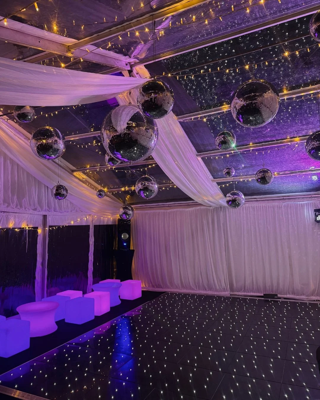 A picture of an LED dance floor in a clearspan marquee with disco balls and twinkly lighting