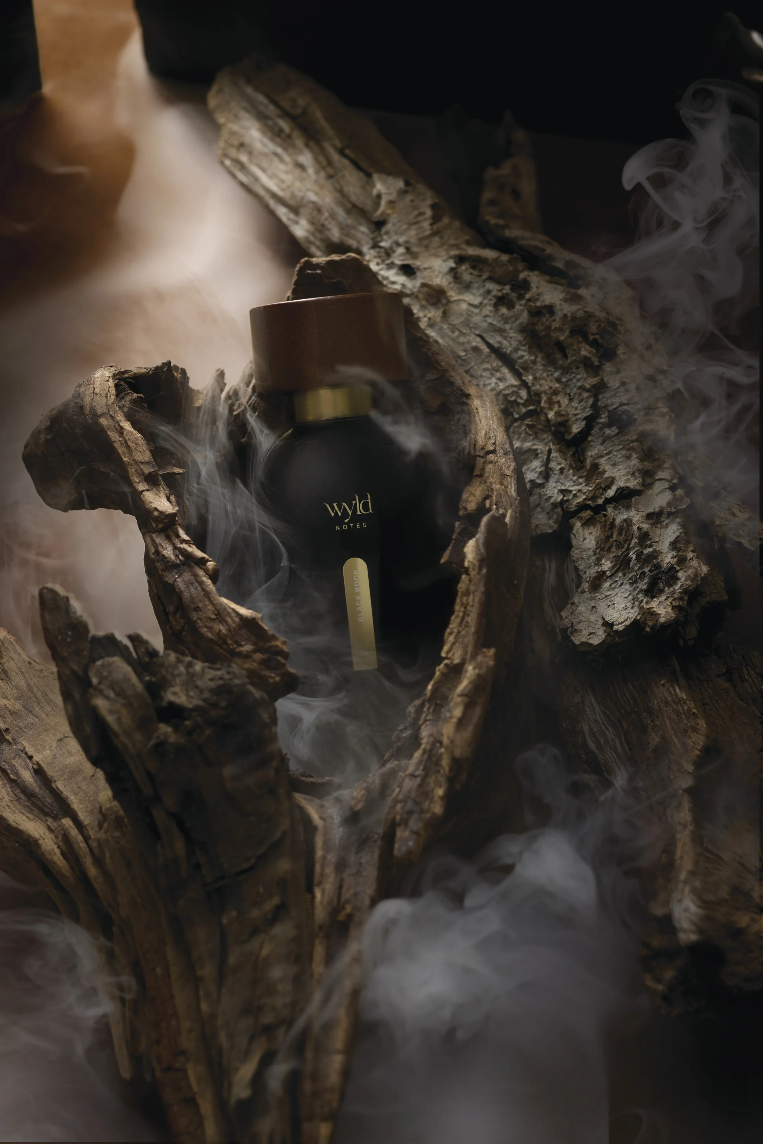 A black bottle with a brown cap labeled 'Wild Notes' placed inside a rustic wood box surrounded by large pieces of wood and swirling smoke.