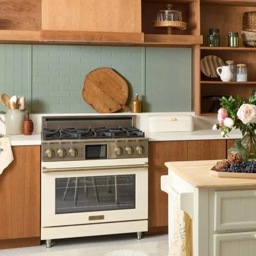 Kitchen with a stove, cutting board, and open shelves with dishes and jars