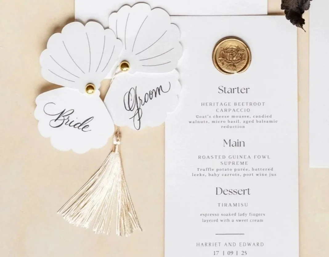 Wedding invitation with tags labeled 'Bride' and 'Groom', gold wax seal, and menu card with appetizers, main course, and dessert options.
