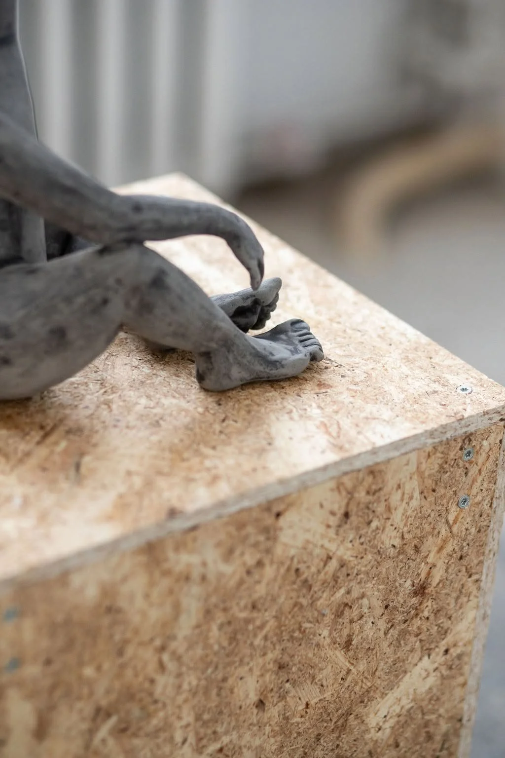 Close up of contemporary ceramic sculpture on a pedestal displayed in the the exhibition SPACETIME  UN[B]LOCKED, featuring feet of human-like bird.