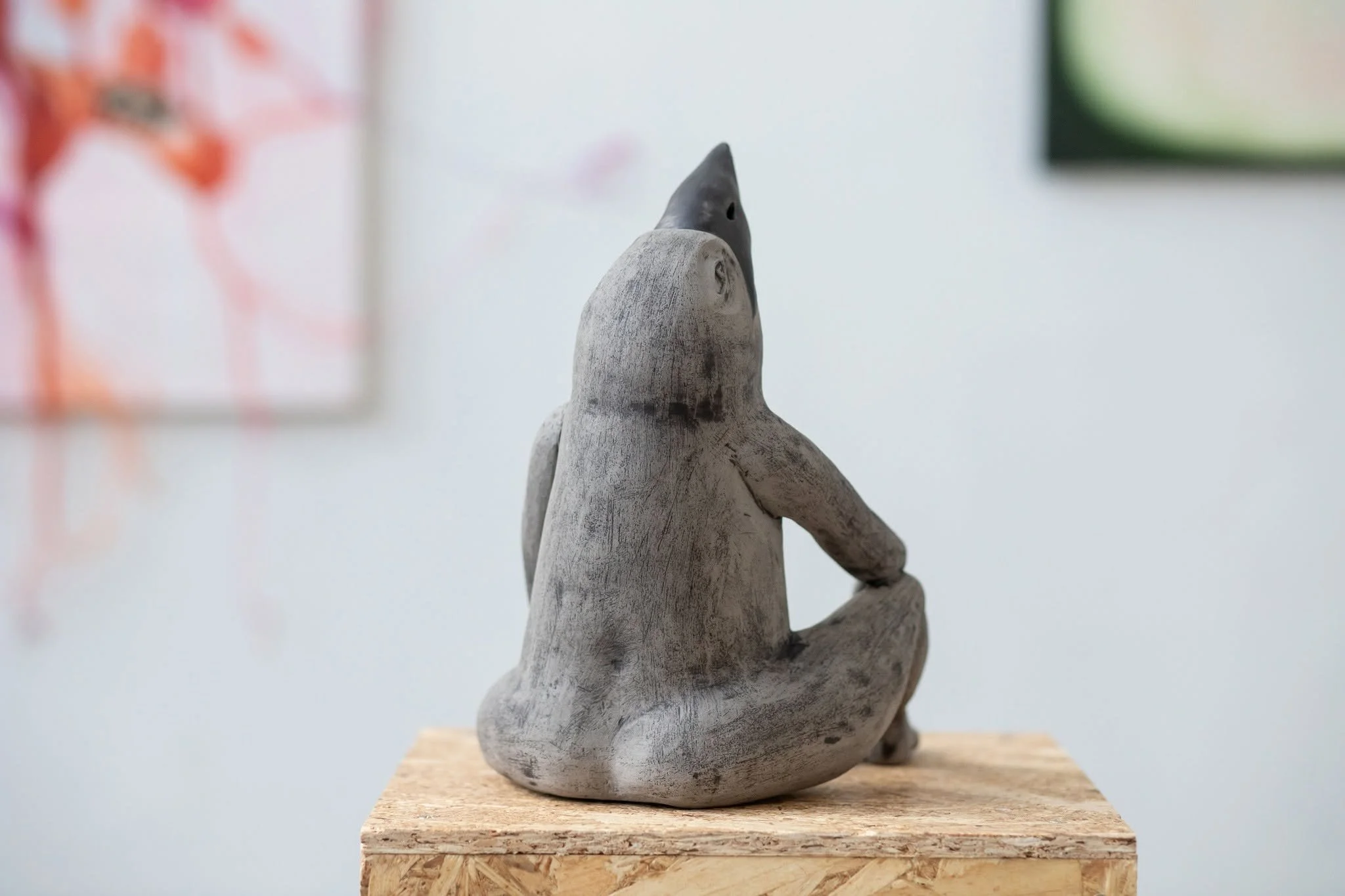 Contemporary ceramic sculpture on a pedestal displayed in the the exhibition SPACETIME  UN[B]LOCKED, featuring close up of a grey bird form from behind.