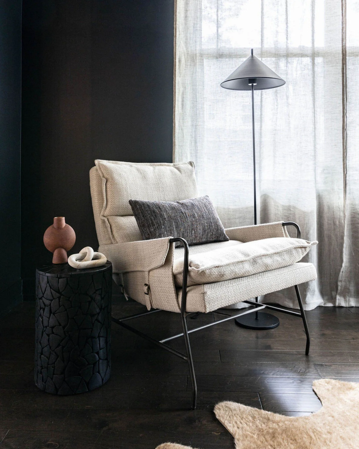 Here, in this space we created a couple of years ago now, character takes center stage &mdash; charcoal-toned walls set a grounding backdrop, a sculptural chair invites stillness, and a carved side table anchors the space. Subtle notes of rust and ca