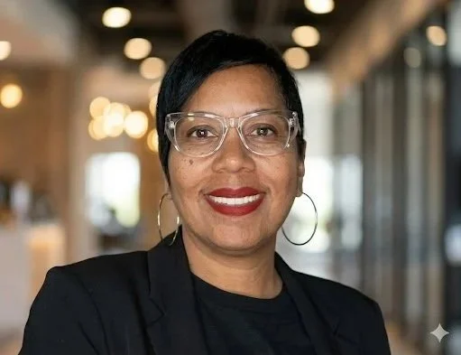 Owner, Tolya Ivory Joseph, founder of PIXSBYIVORY PHOTO BOOTH, smiling with short black hair, glasses, and hoop earrings.