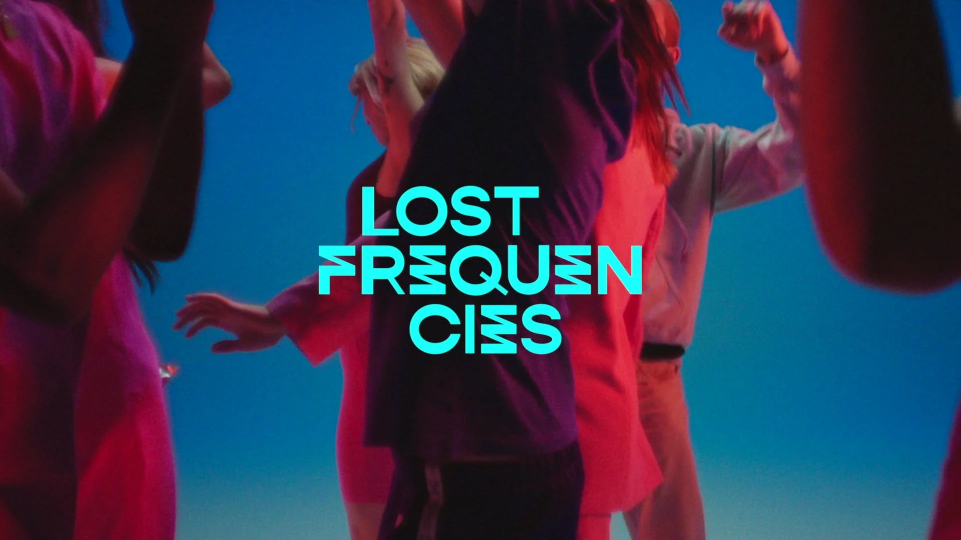 Colorful group of people with their hands raised, facing each other in a circle, with bright blue and pink lighting, and the text 'Lost in the Quums' overlayed in bright cyan.